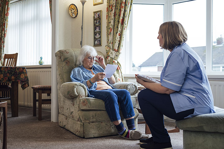 Nurse and older lady sat together in care home
