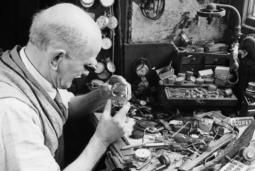 An old black and white photo of someone making a shoe
