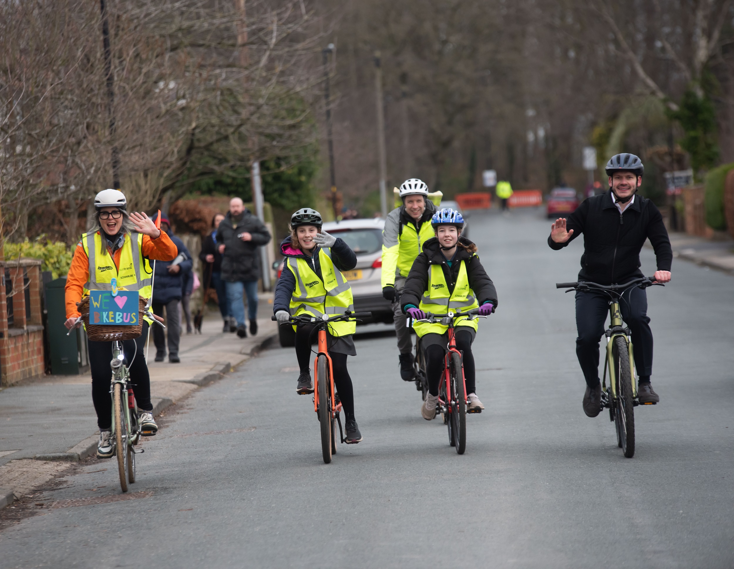 Group of adults and children riding their bikes on the road