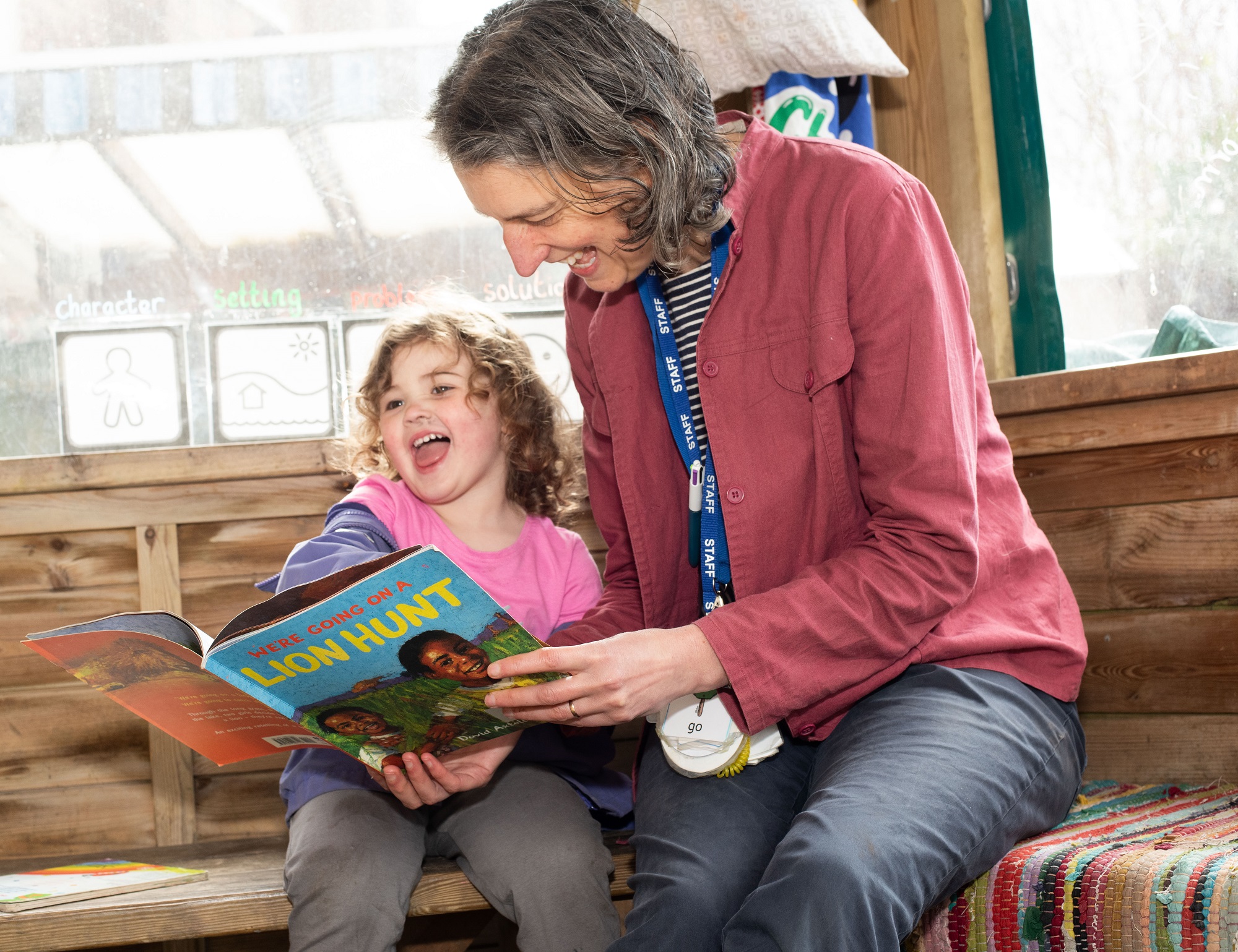 Teacher and child sitting reading We're going on a lion hunt book