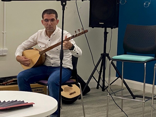 Photo of an adult sitting on a chair playing a musical instrument