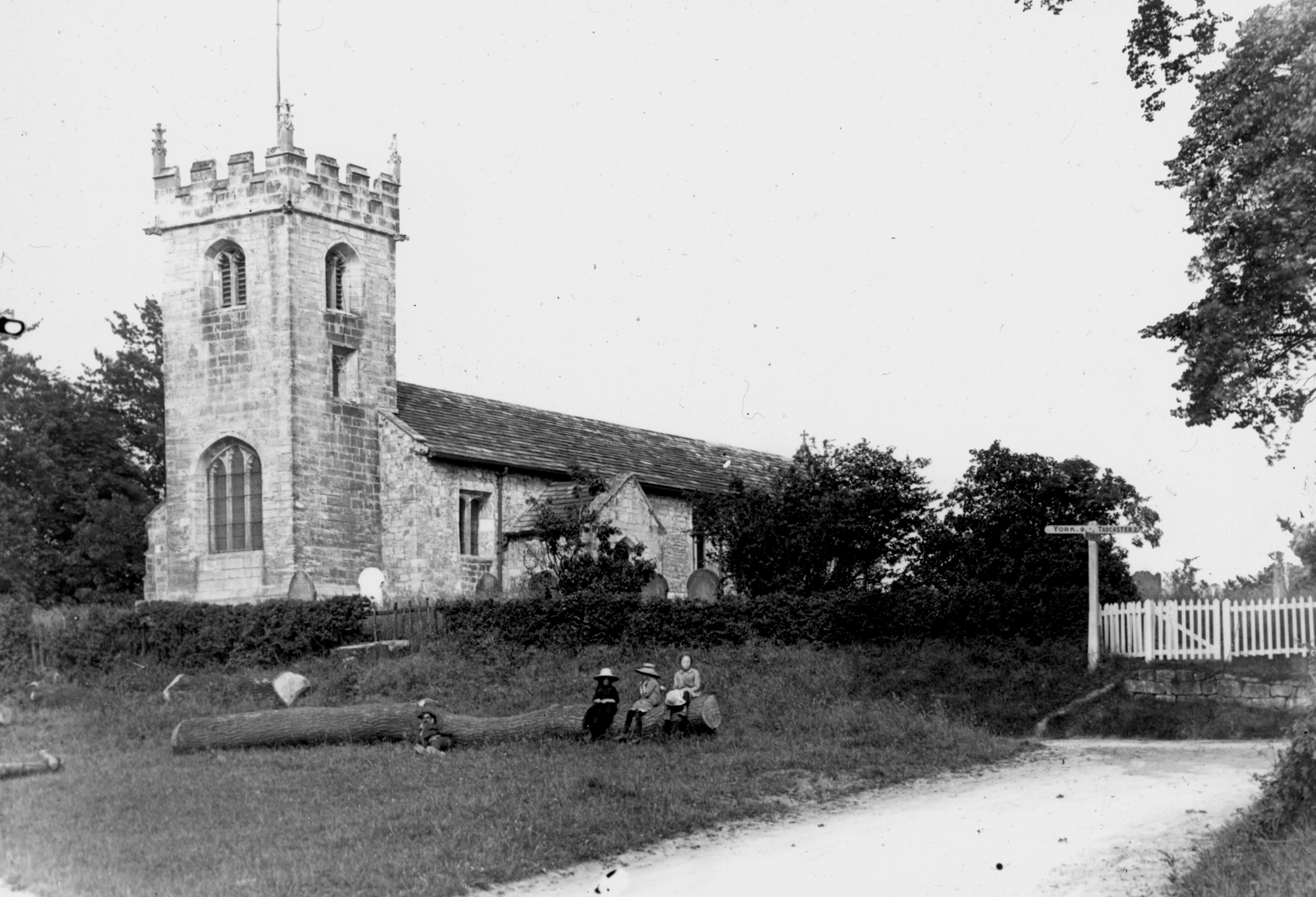 Children on a log outside All Saints’ Church, Wighill, near Tadcaster, in 1914
