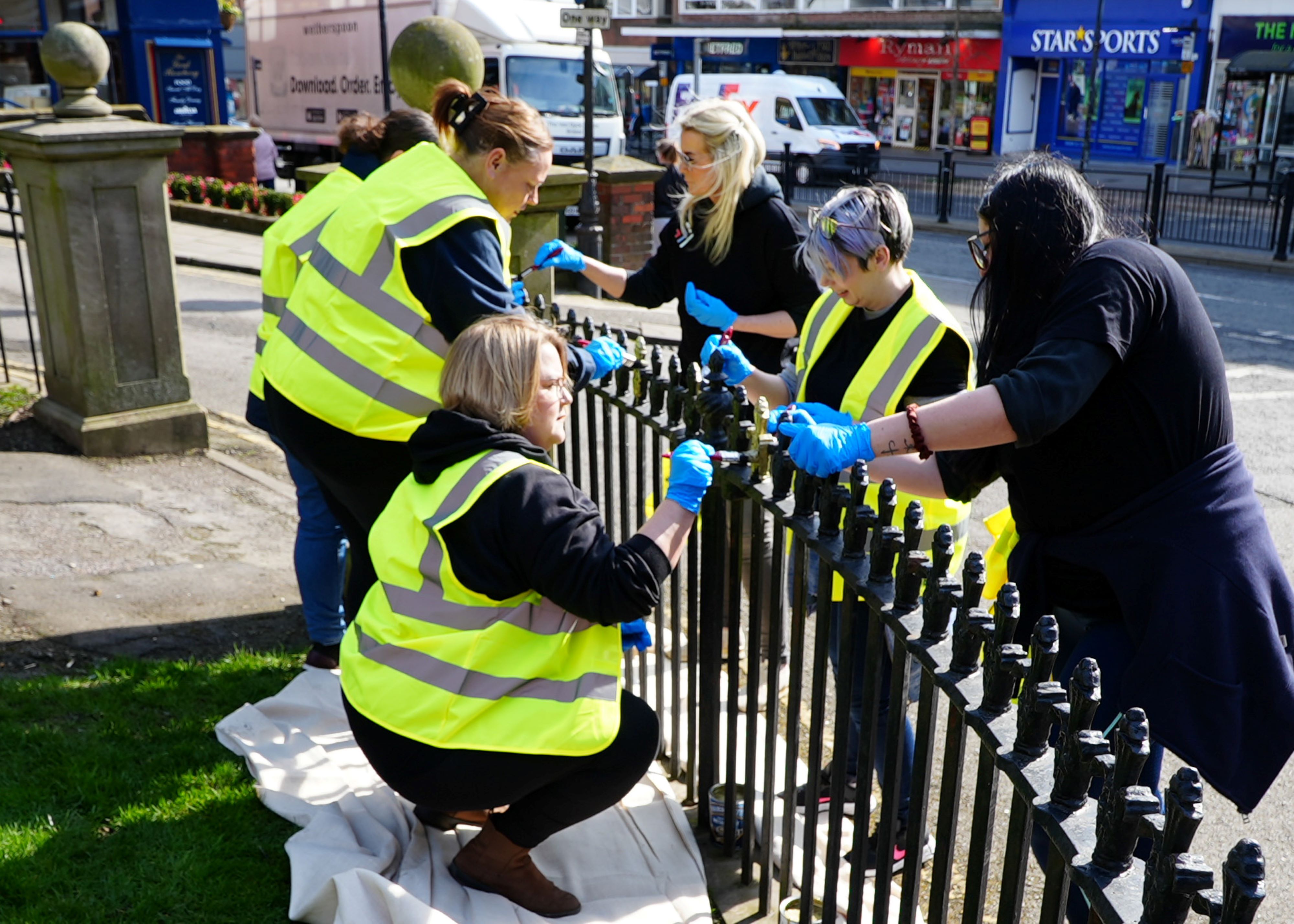Six people painting a fence