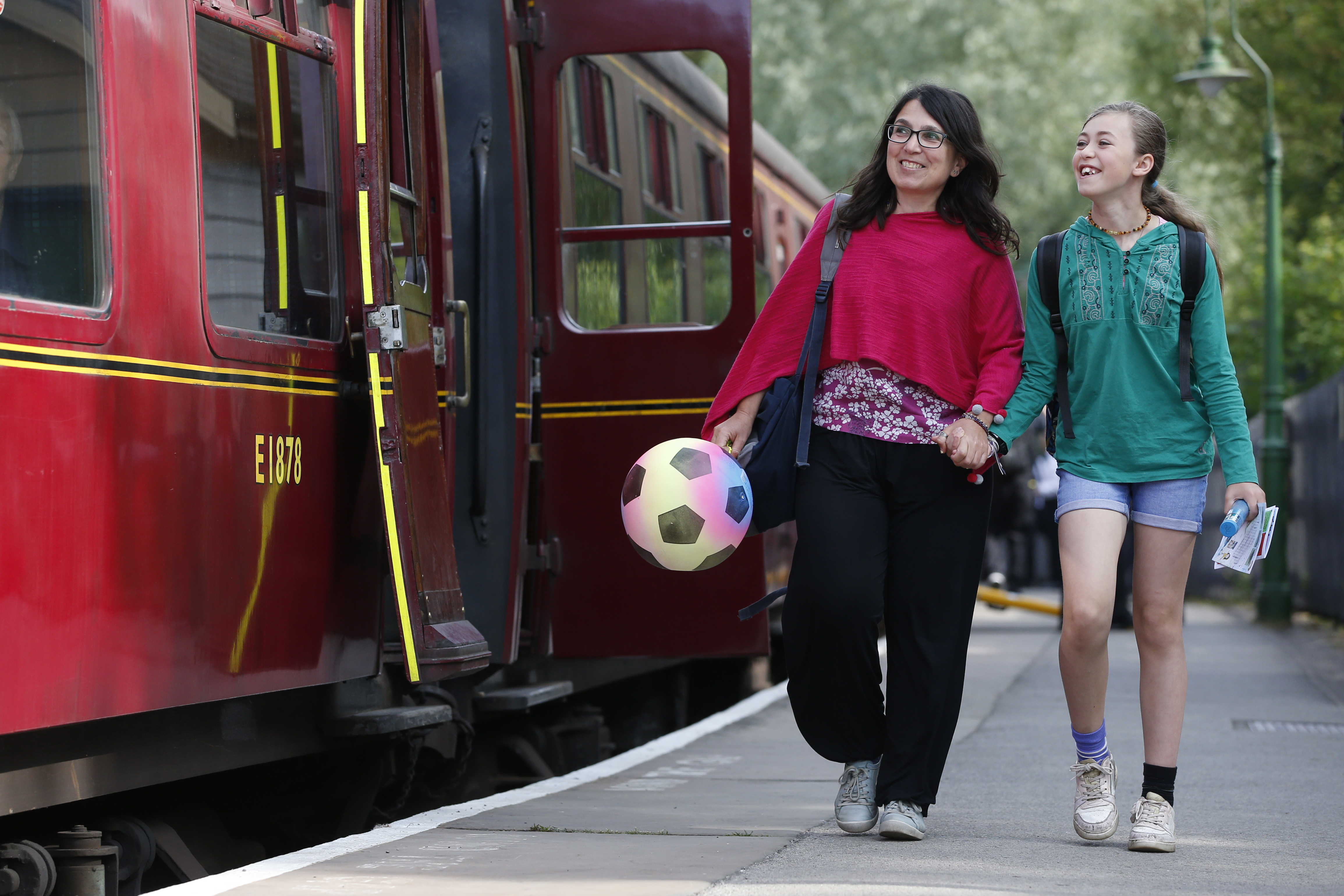 Two people smiling walking alongside a stationary train