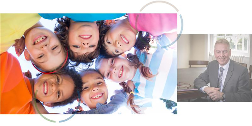 Group of children looking down smiling with a photo of Richard Flinton to the right