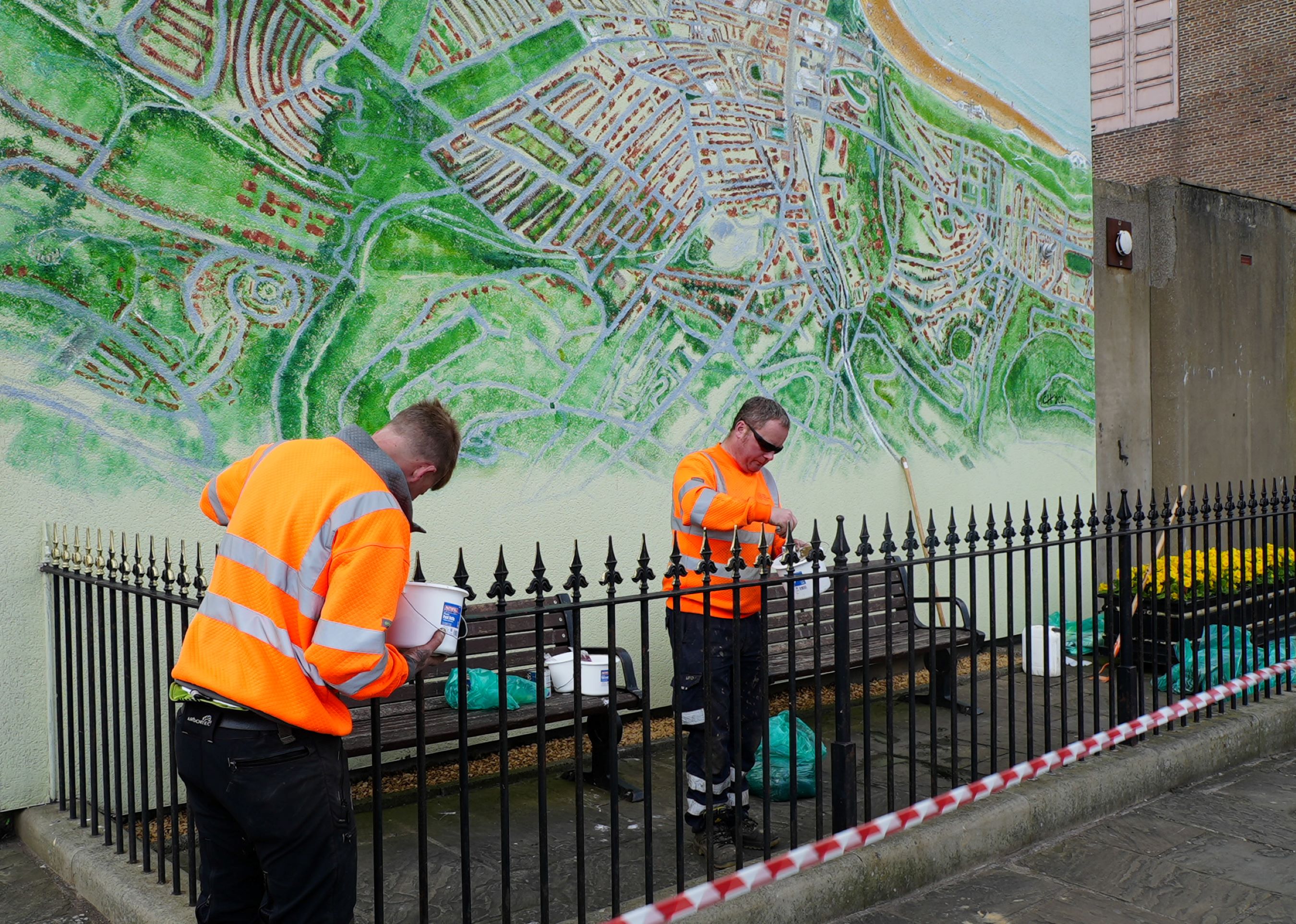 Two people painting the metal railings in Scarborough