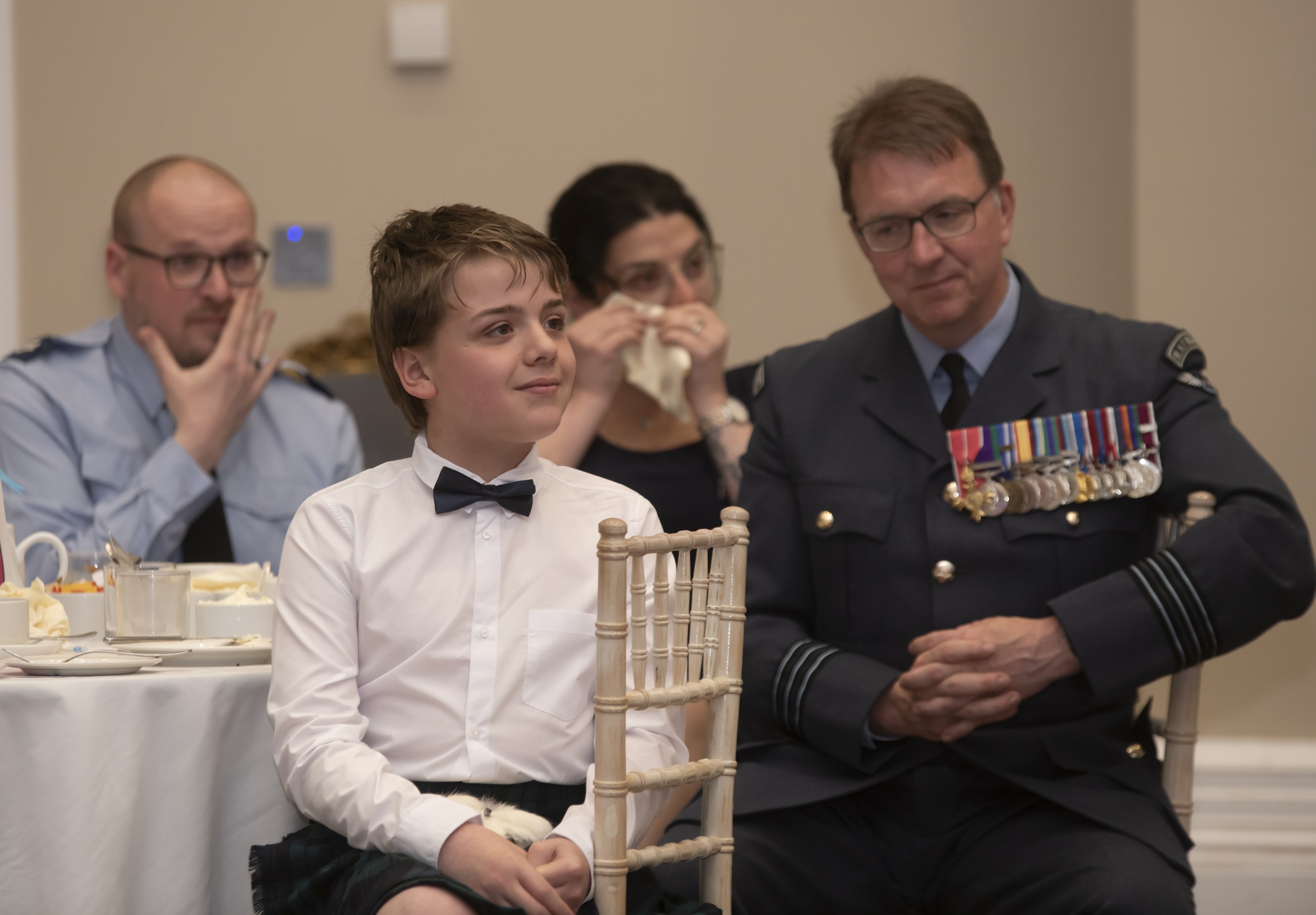 Finlay sitting at the table at the Awards ceremony with family in the background