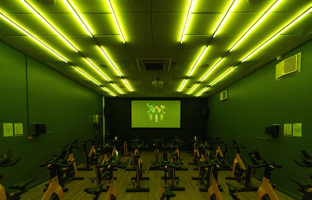 The spin room class at Stokesley Leisure and Wellbeing Hub with stationary bikes illuminated in green from the ceiling lights