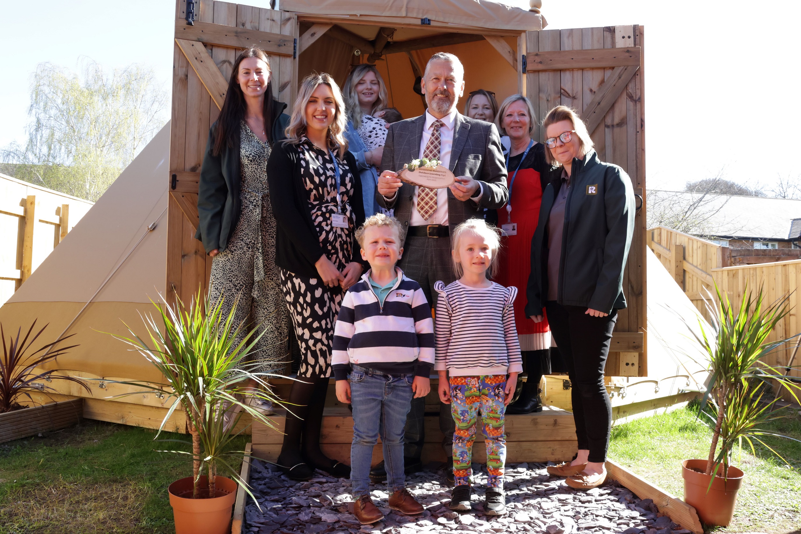 Group of adults and children standing in front of tipi