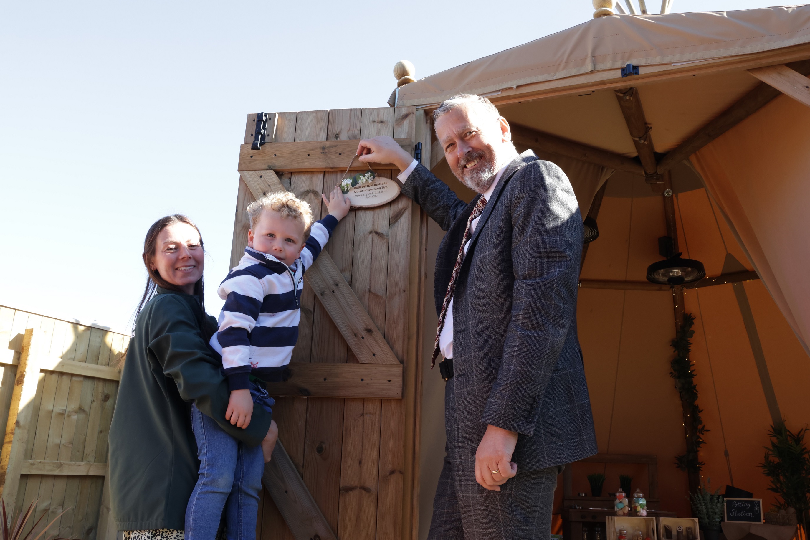Three people hanging a sign on the tipi door