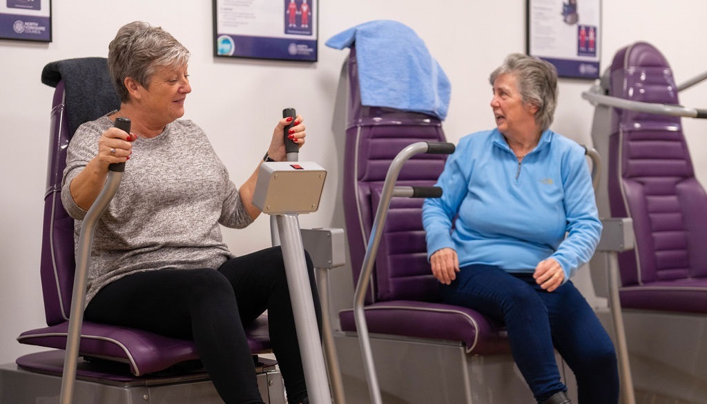 Two women sitting in assisted exercise machines at Northallerton Leisure and Wellbeing Hub's wellbeing suite
