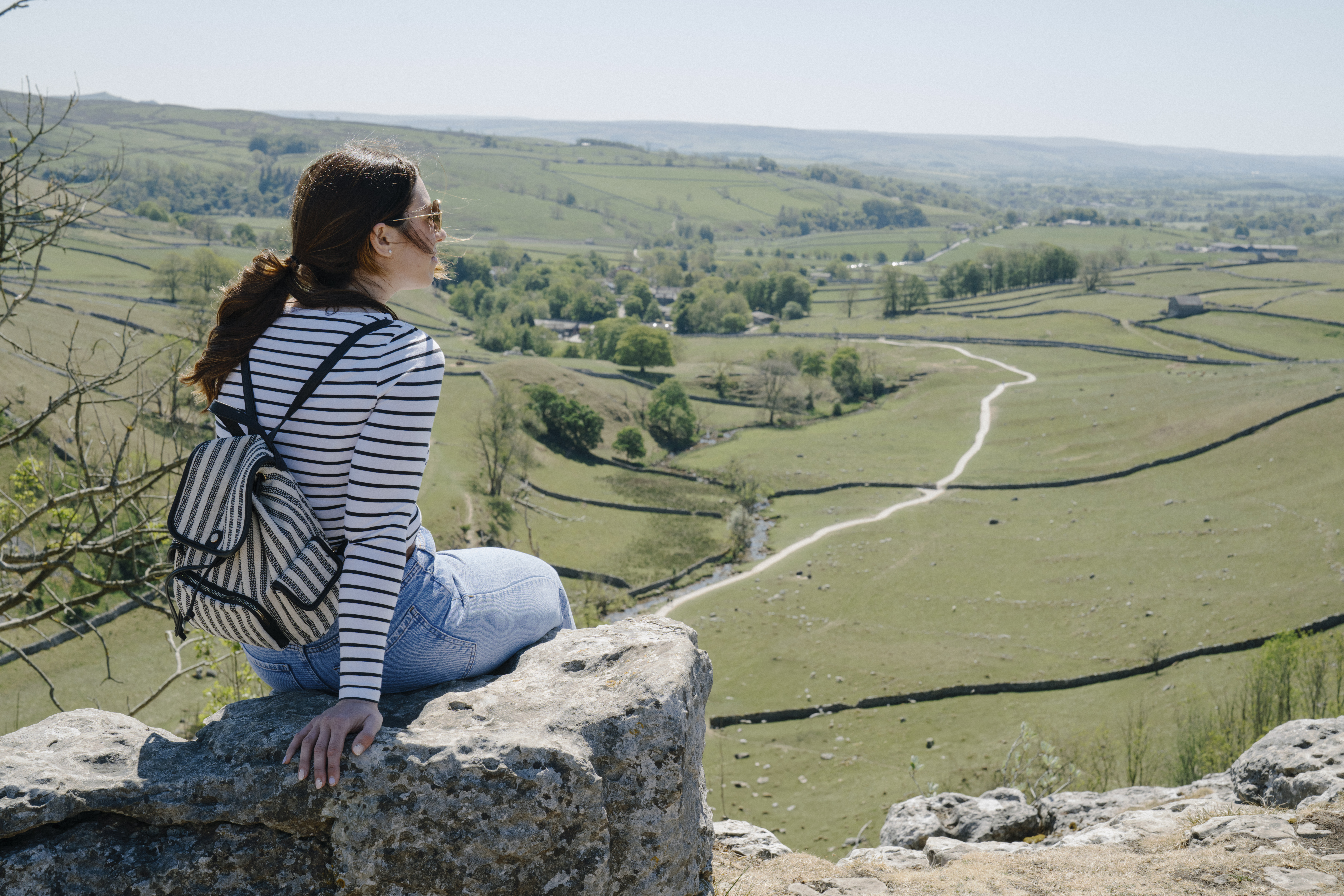 Person sitting on a rock, looking out over the Yorkshire Dales. Tom Arber and Visit North Yorkshire