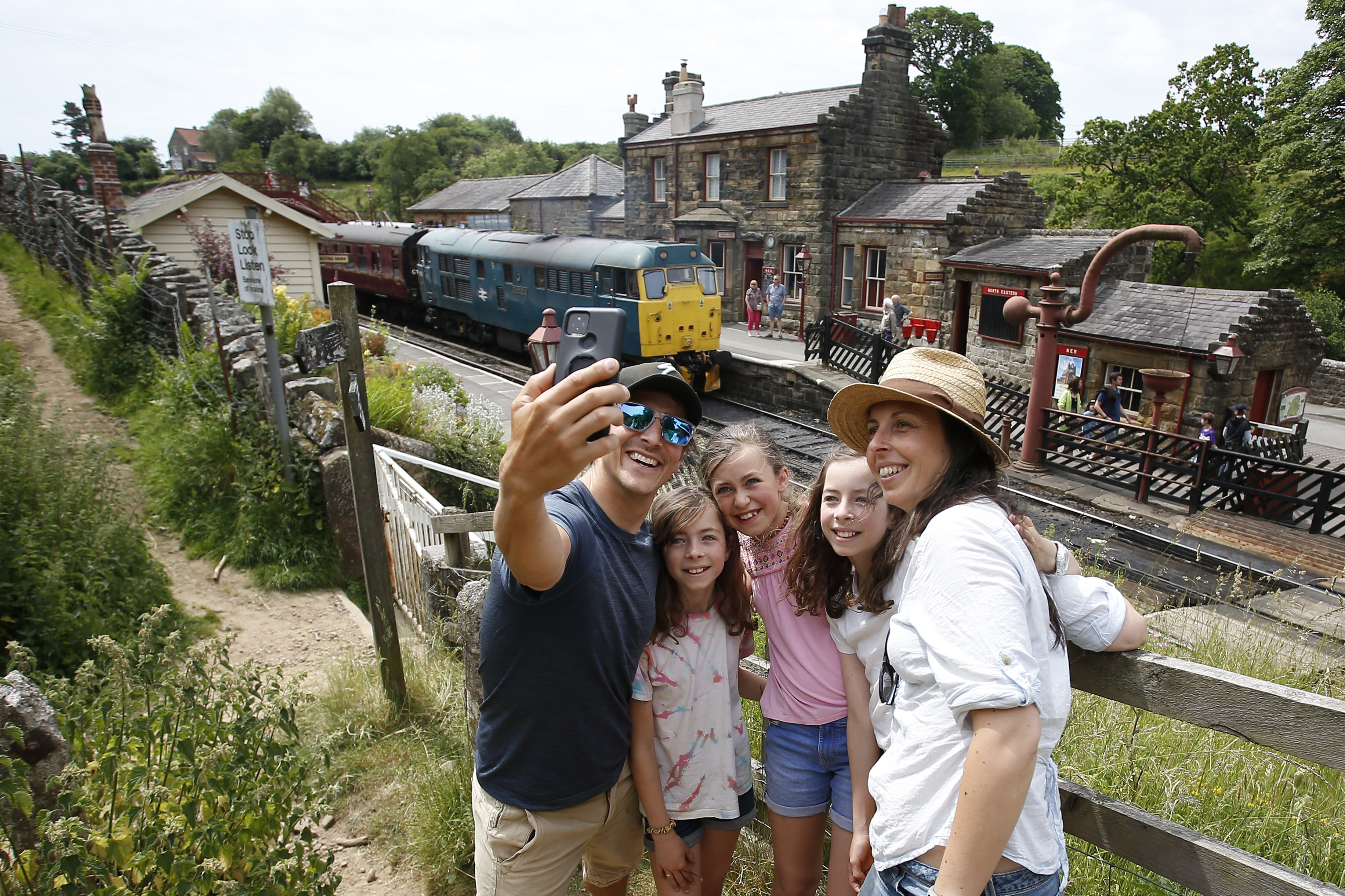 Family taking a photo on a mobile phone with a train in the background