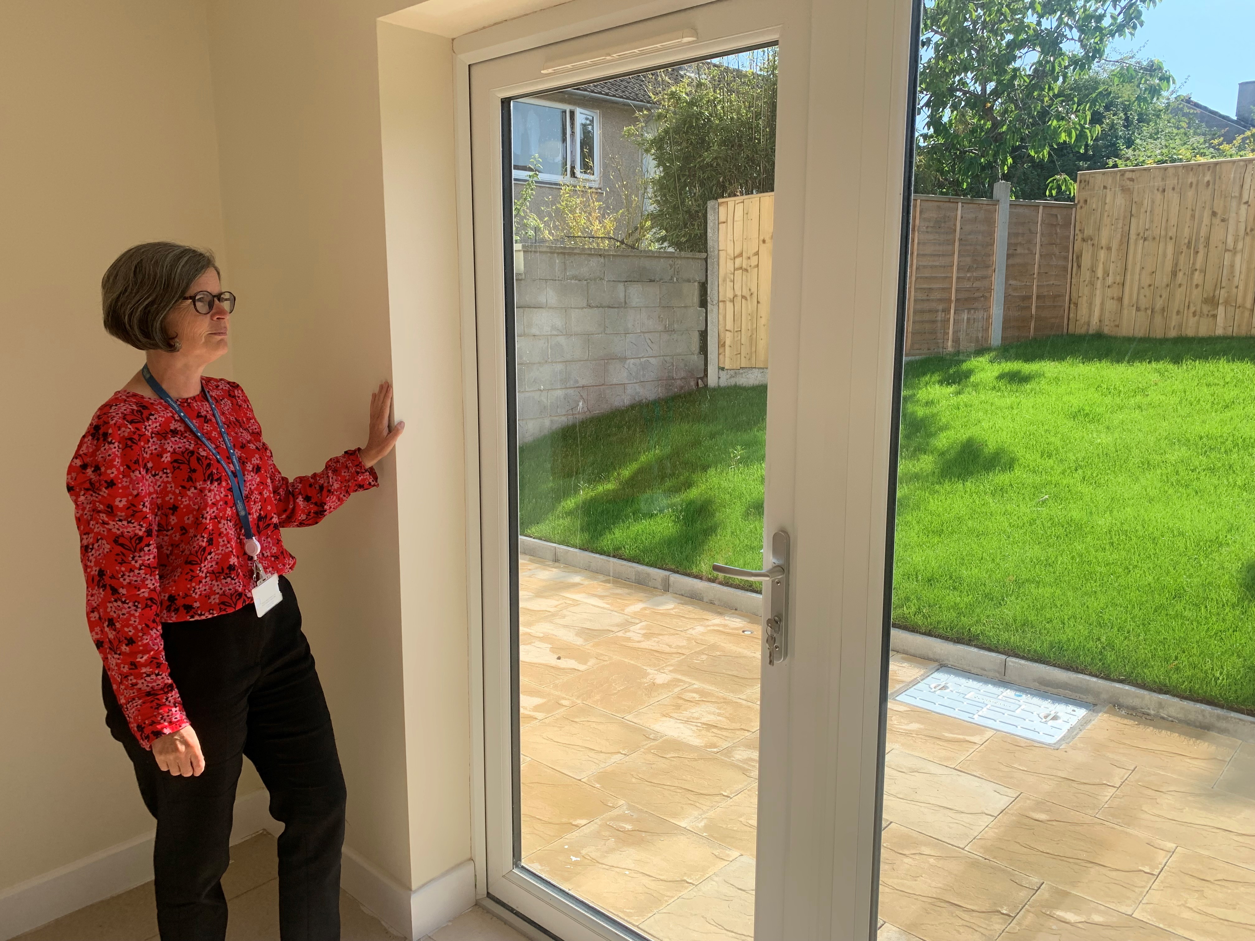 A lady looking out patio doors in towards a garden