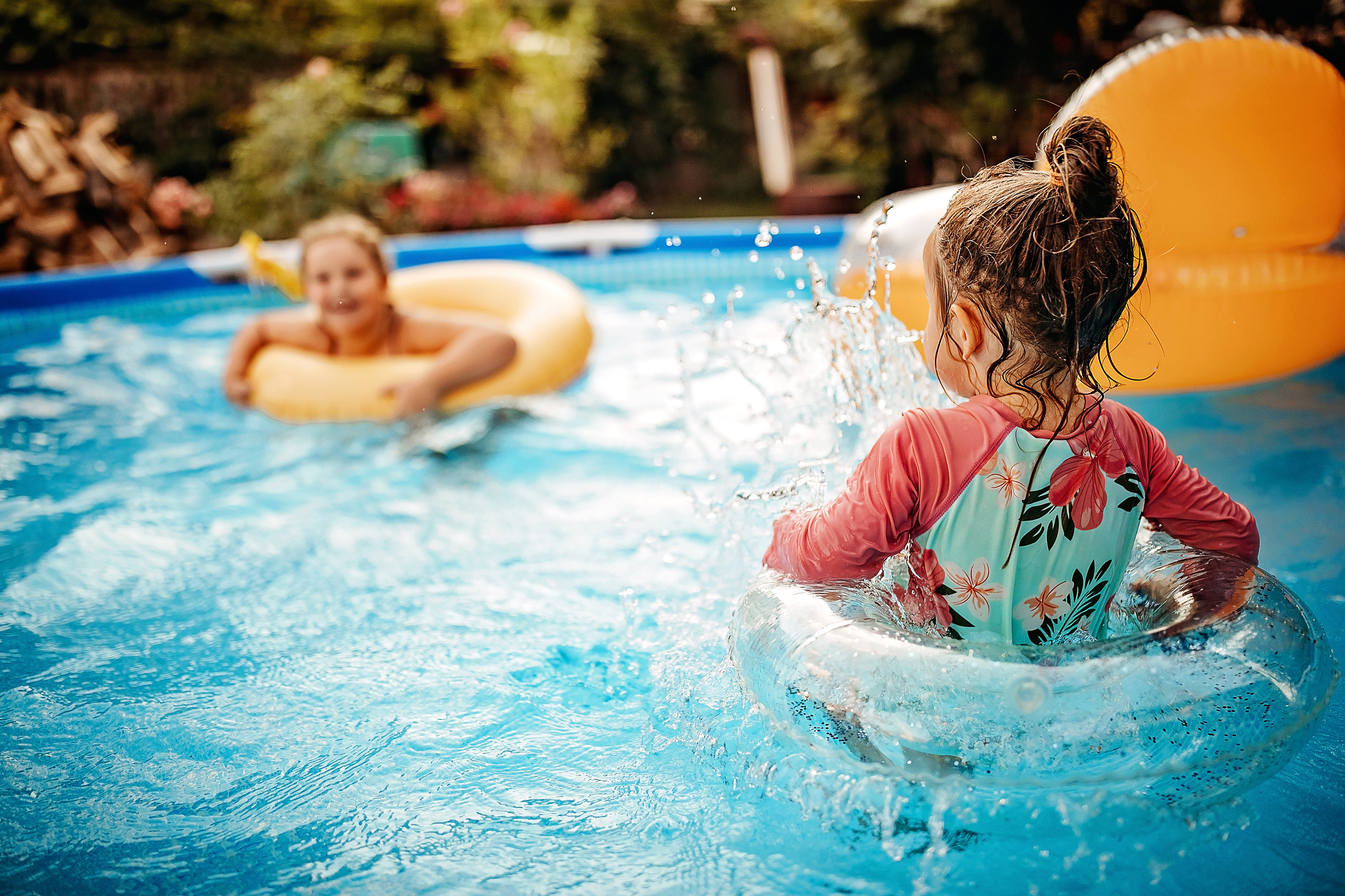 Two children in rubber rings having fun in a paddling pool