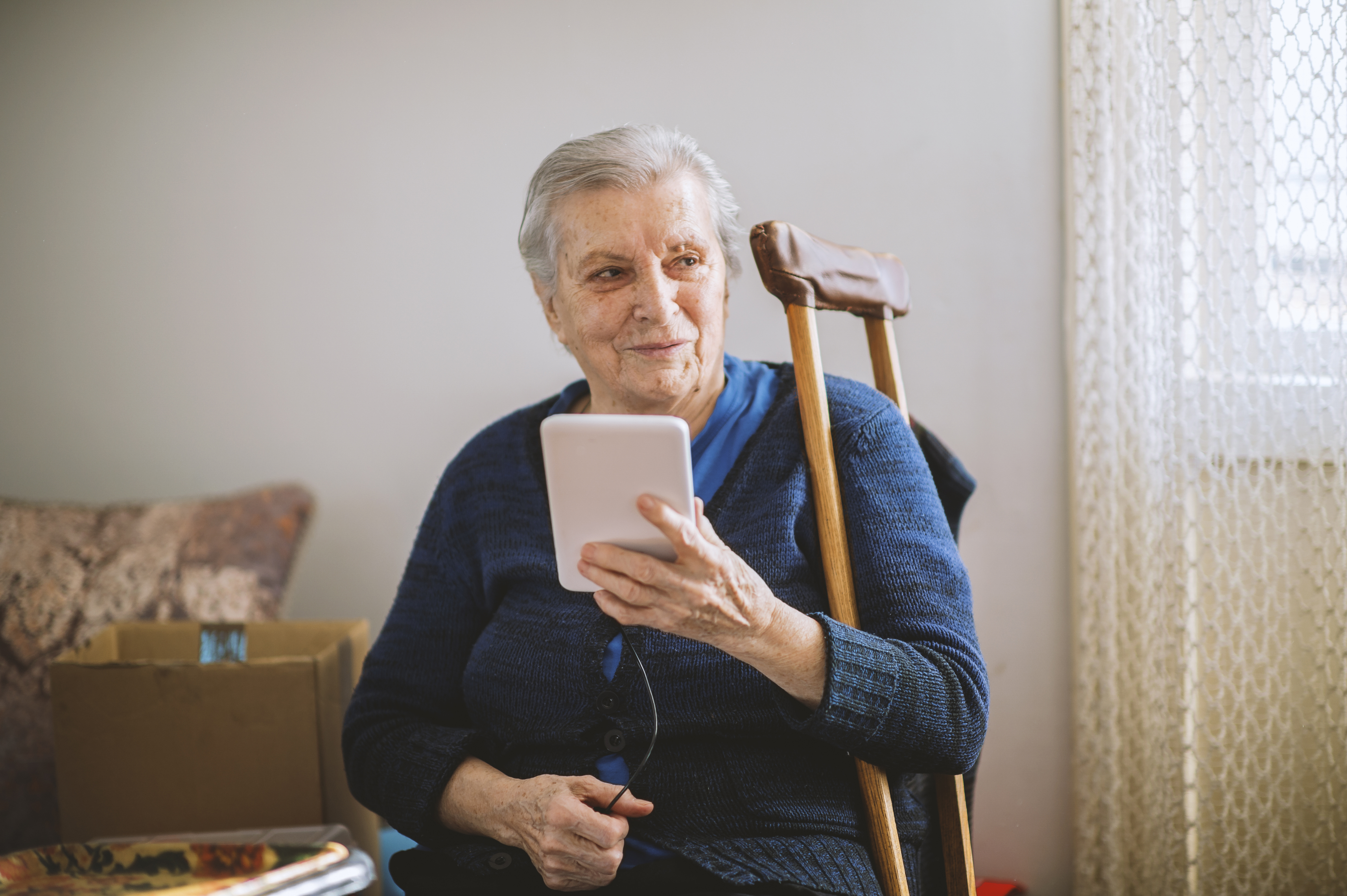Adult sitting down holding a small portable device.