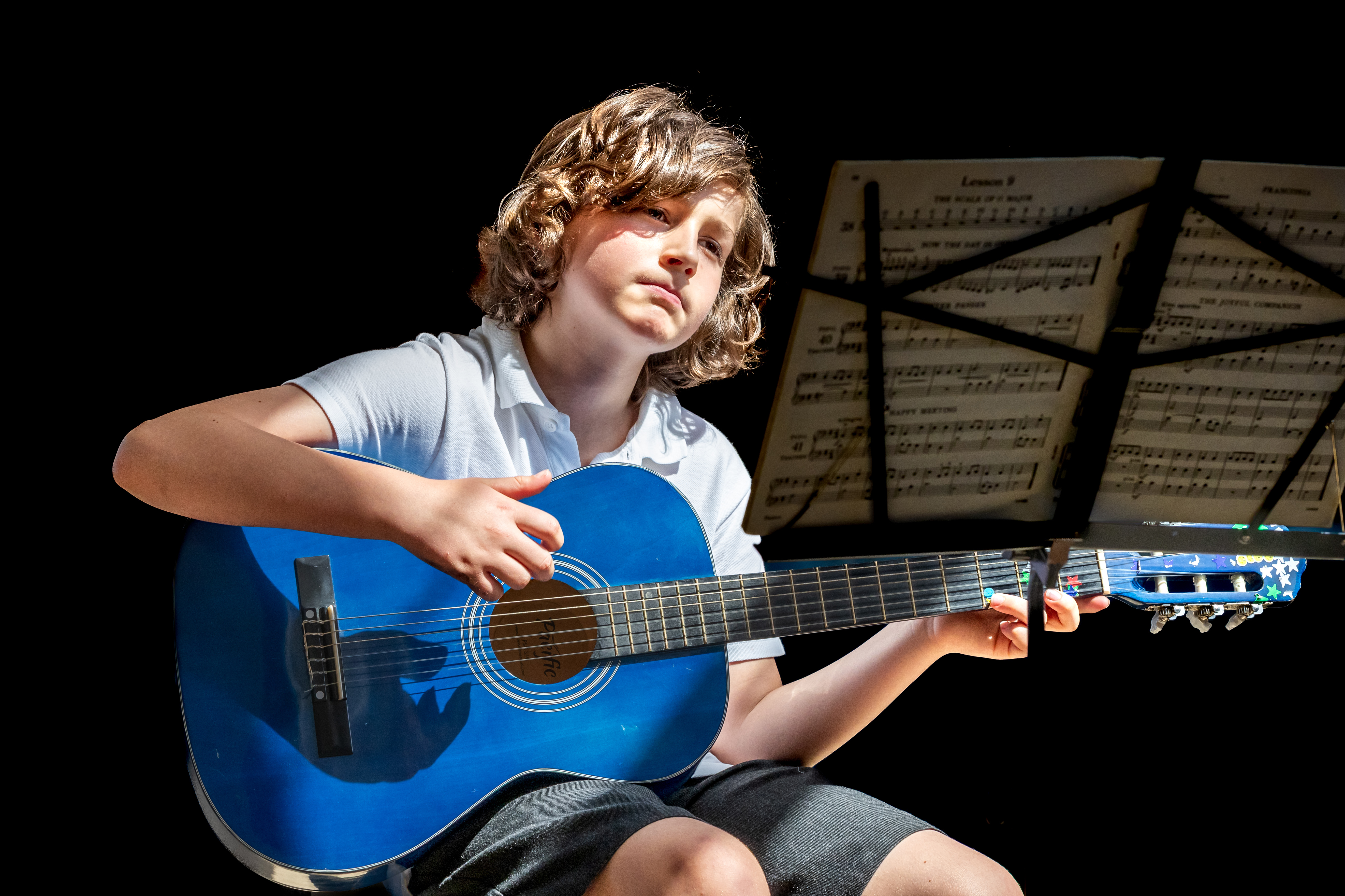 Child sitting playing a guitar