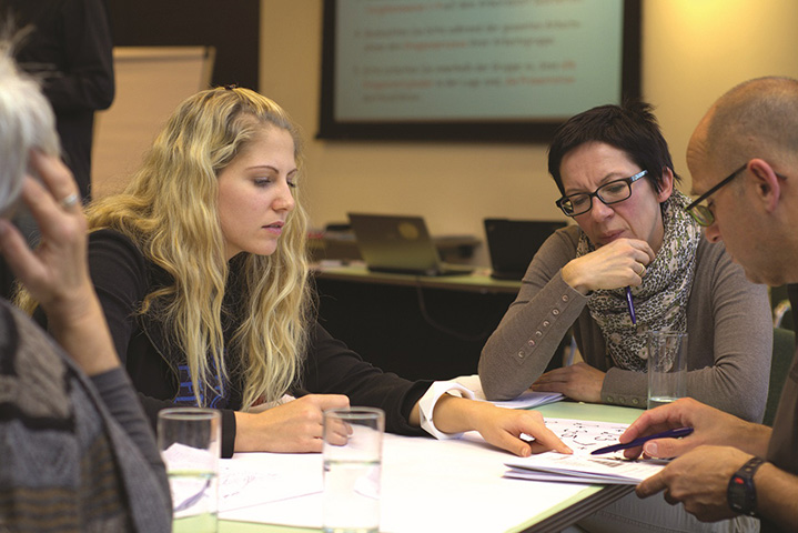 Adults sat around a table looking at information and paper