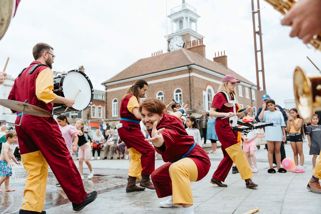 Group of people playing musical instruments outside to surrounding people