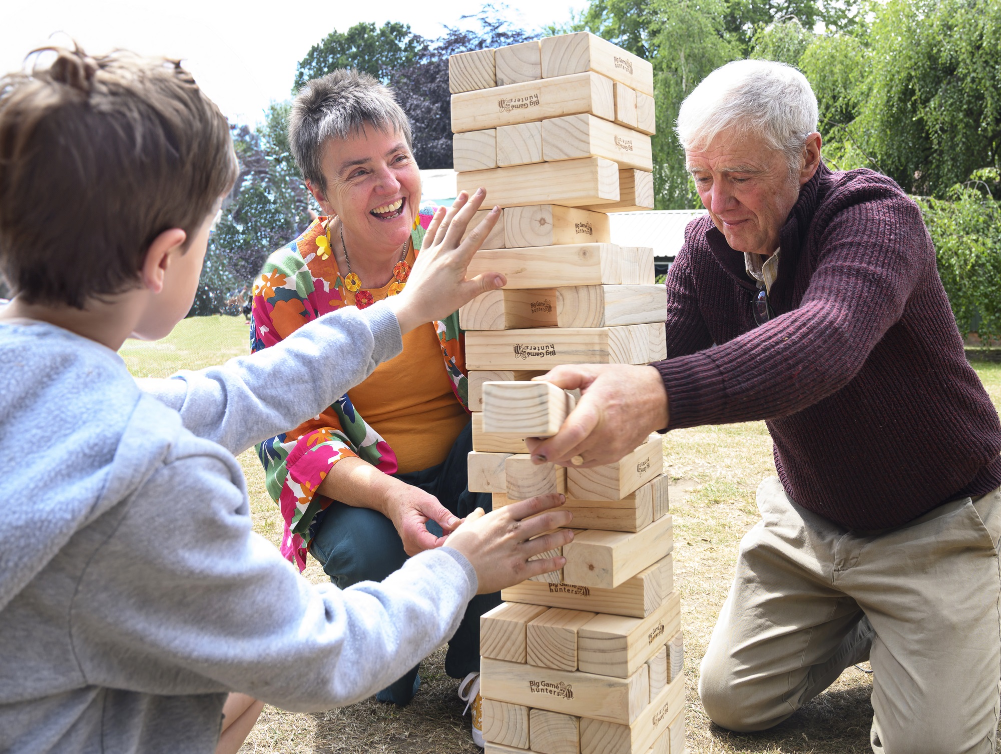 Two older people and young child playing Jenga