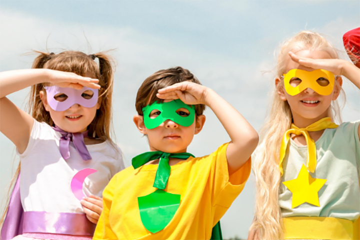 Three young children dressed in bright super hero costumes