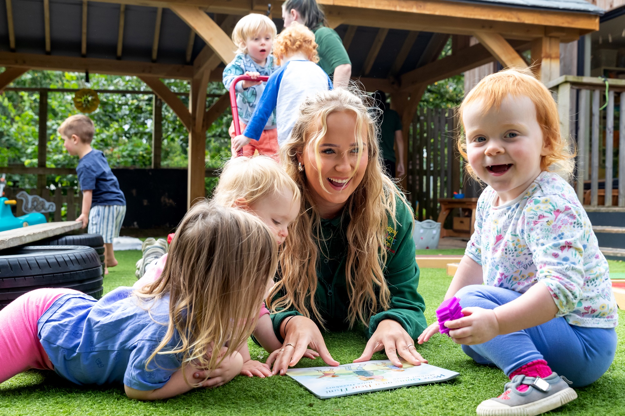 Children reading with a nursery practitioner.
