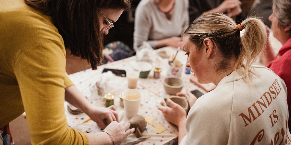 Group of people enjoying pottery around a table. Credit Rebecca Norris