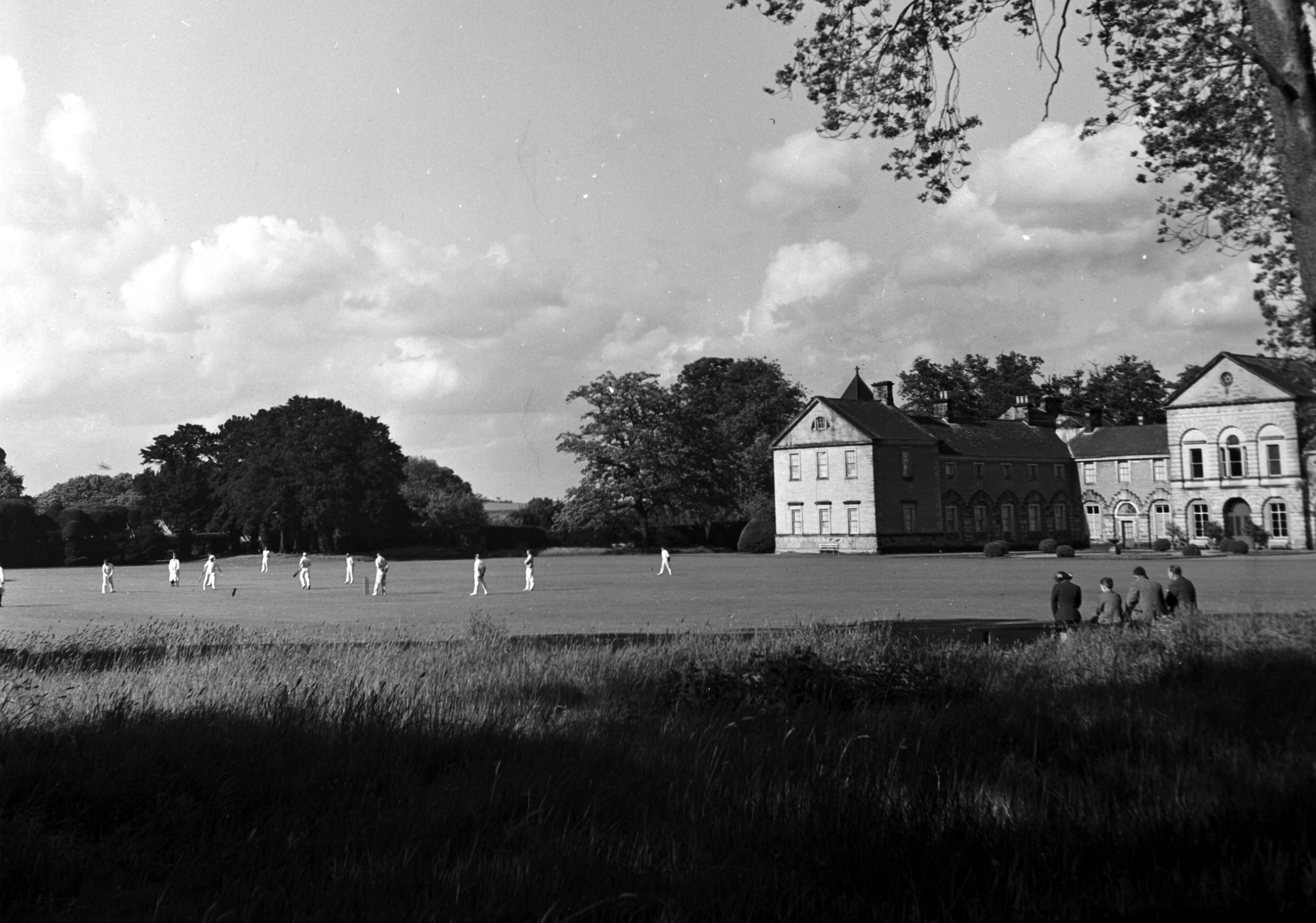 Black and white photo of cricketers playing on the lawn of Hovingham Hall