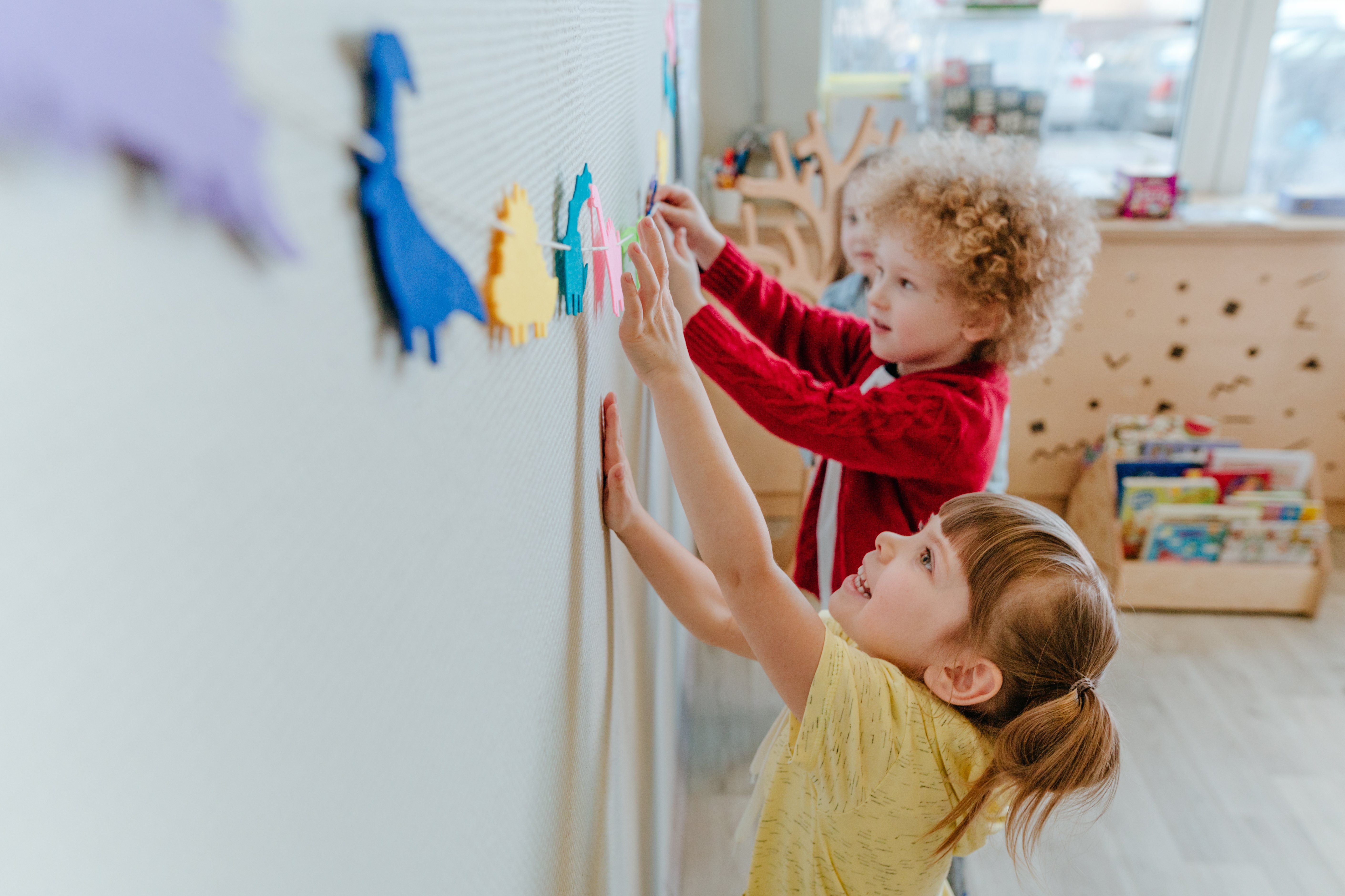 Children sticking animals to a wall
