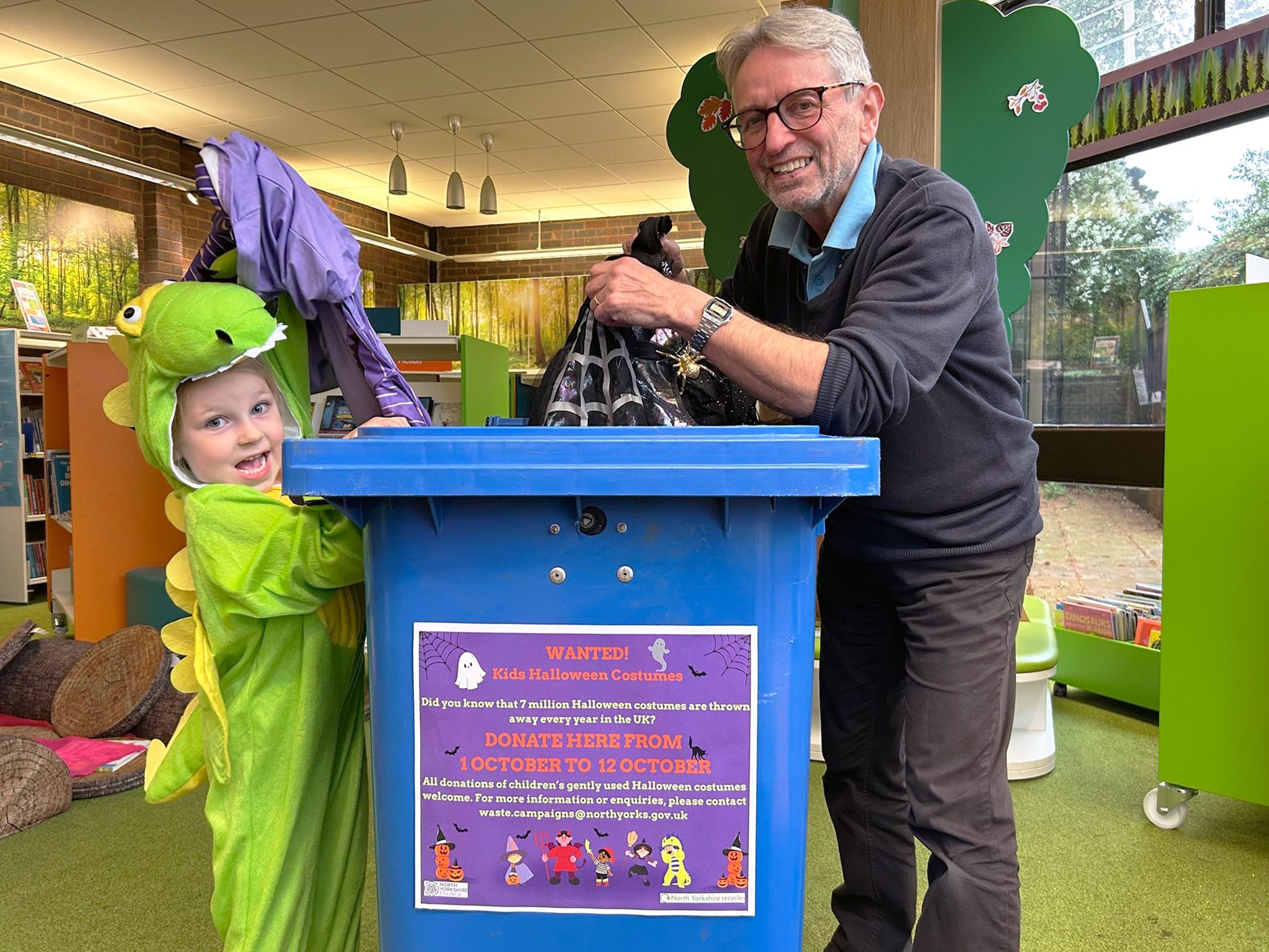 A man and child with a costume recycling bin
