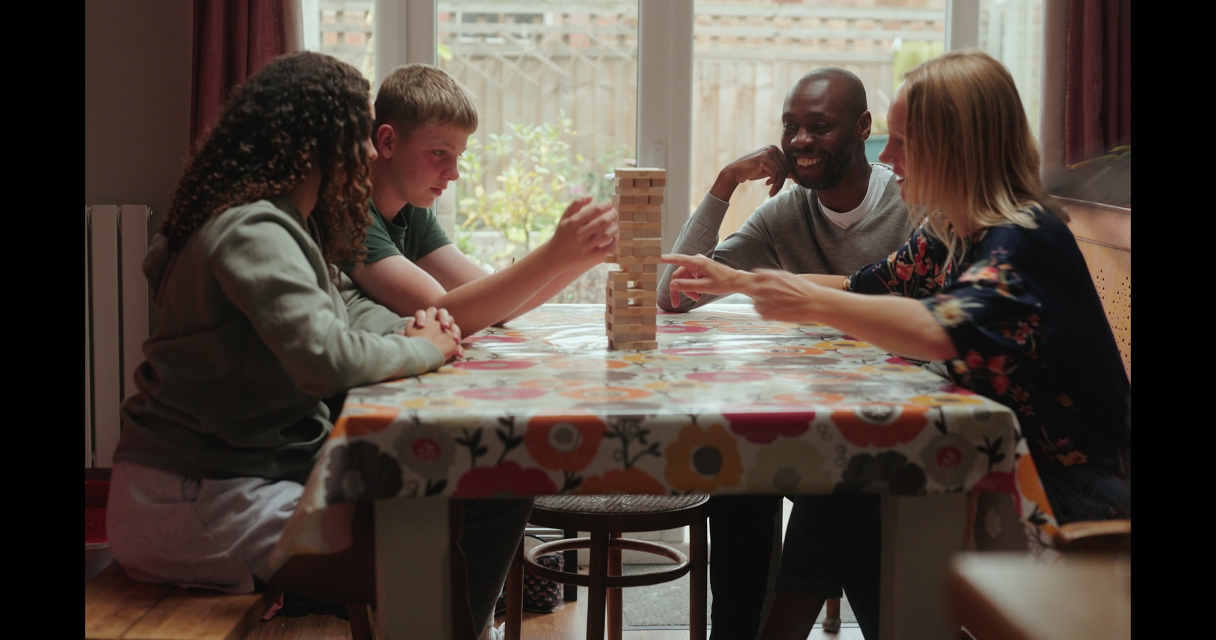 Four people at a table playing Jenga