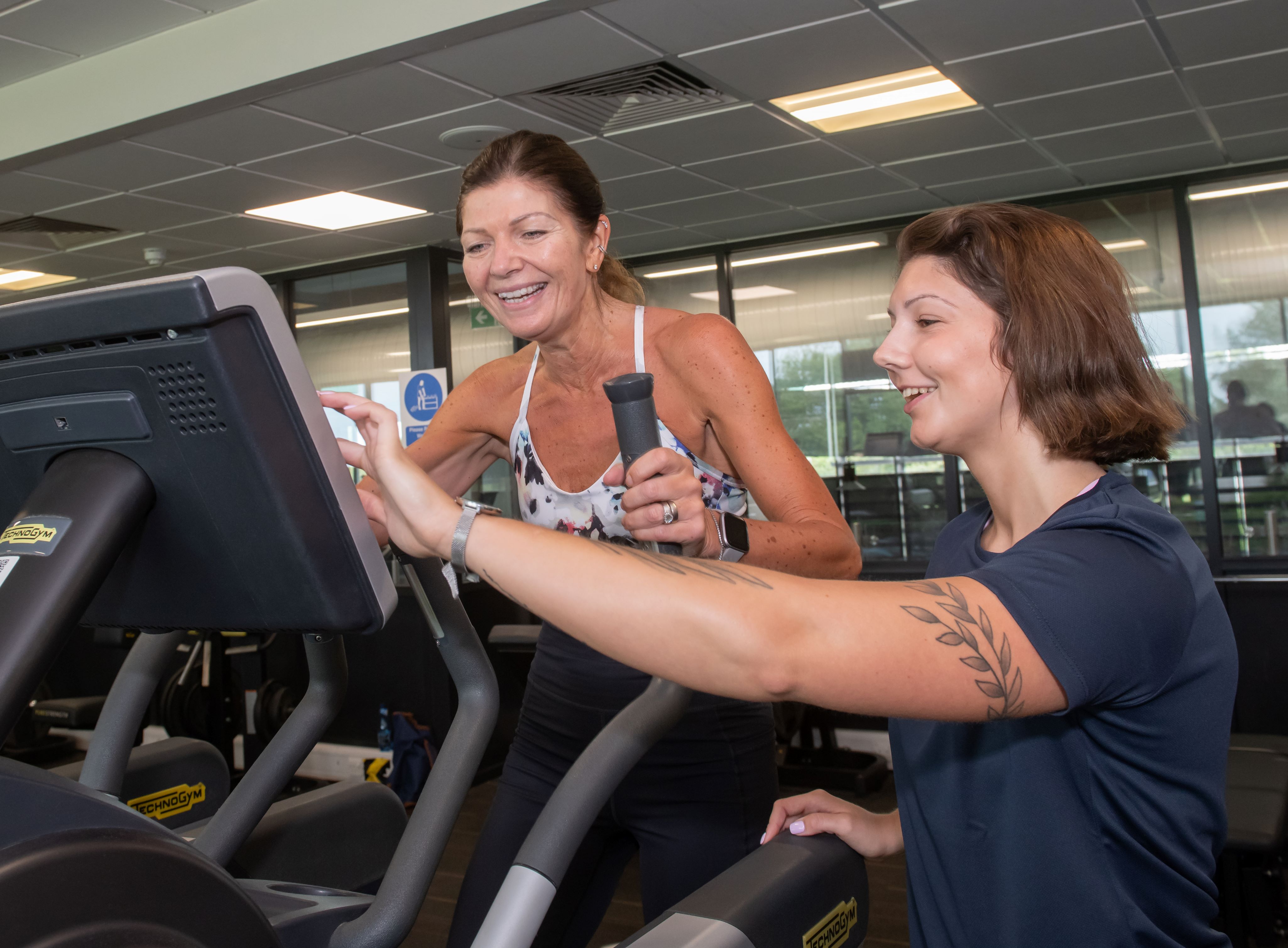 A gym instructor with a lady on a cross trainer