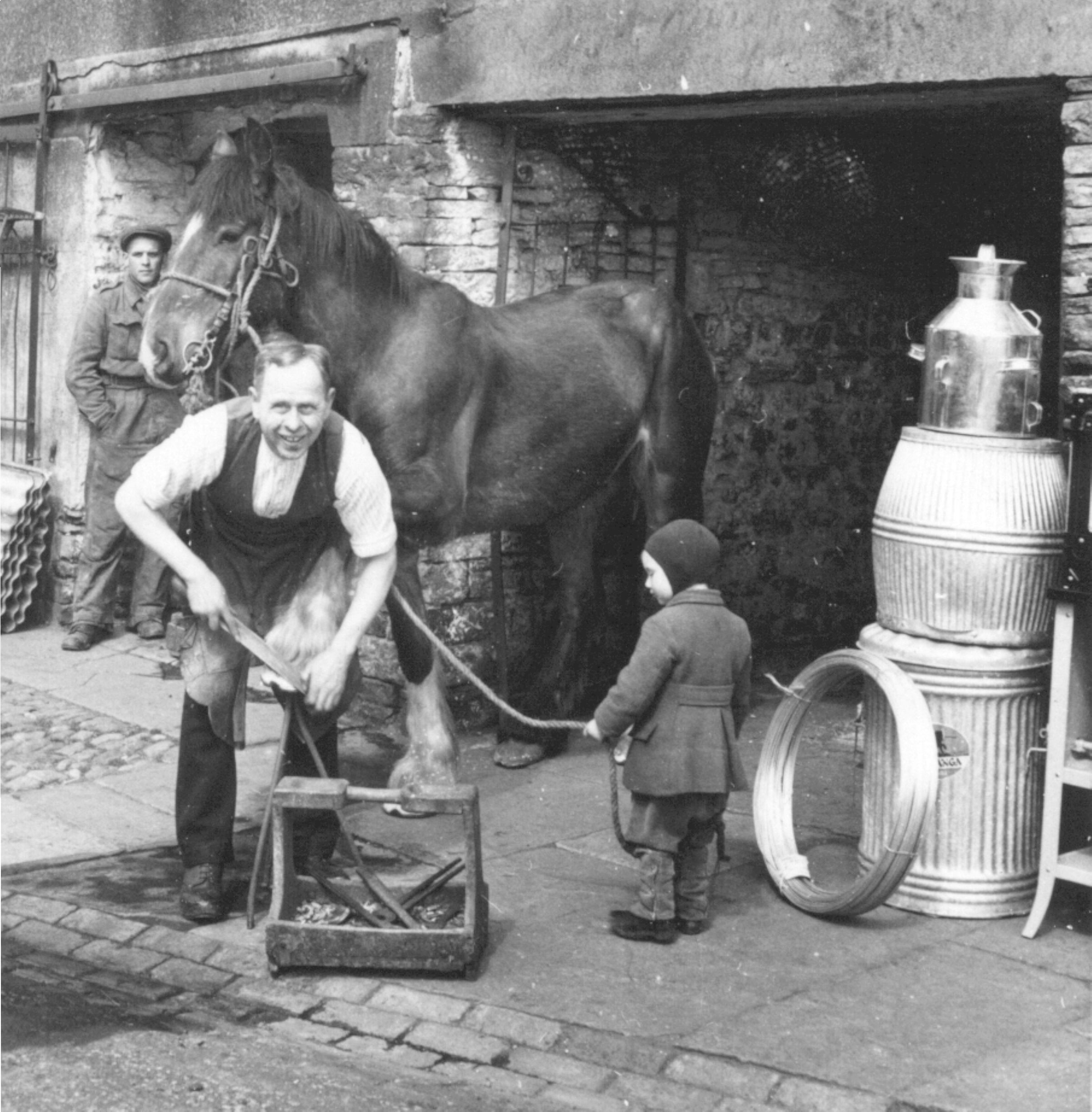Blacksmith Bob Spencer, shoeing a horse at his smithy in Hawes (mid-20th century). From the Bertram Unné photographic collection.