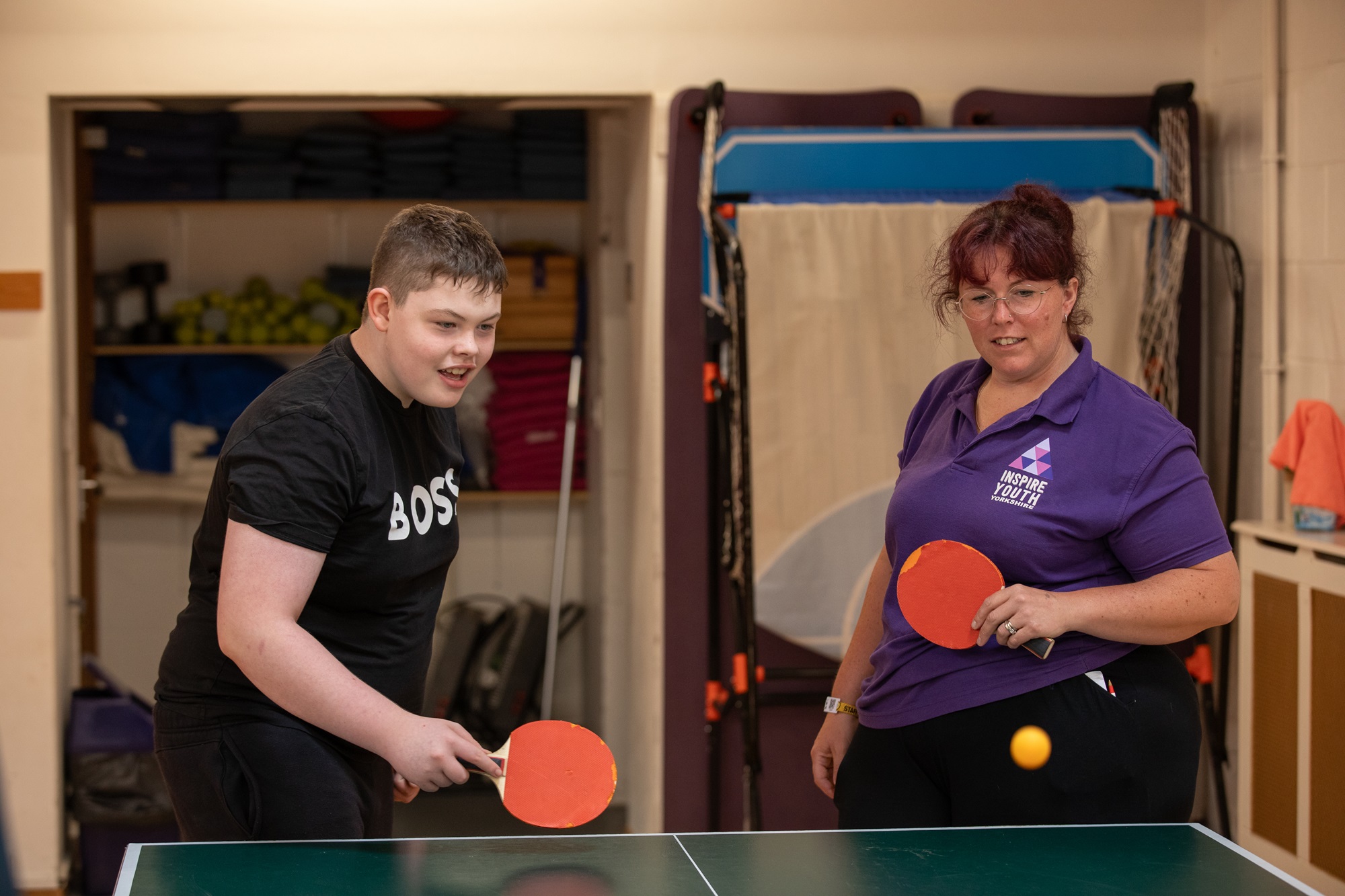 A lady and teenage boy playing table tennis 