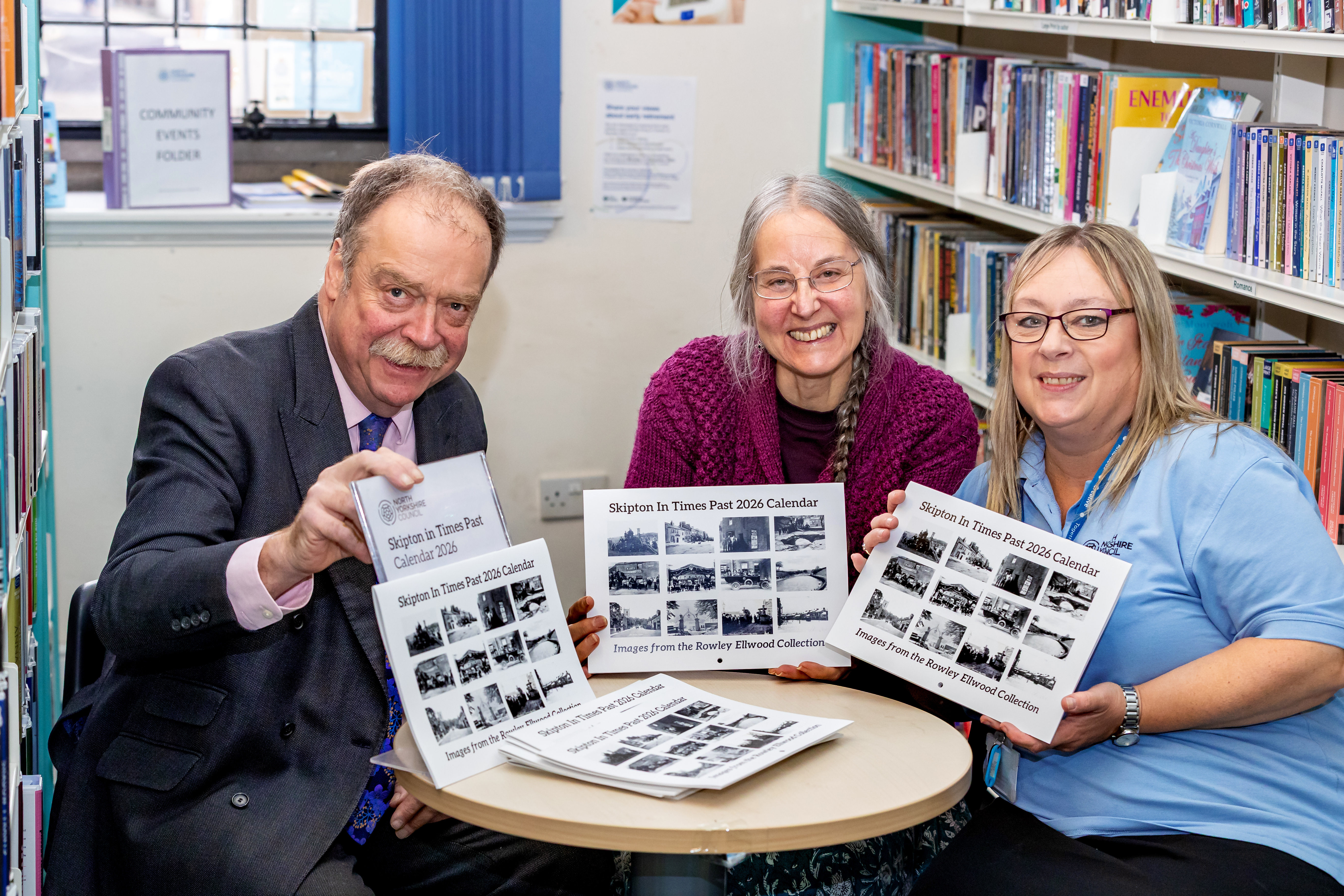 Councillor Myers with two colleagues sitting at a small round table looking at calendars