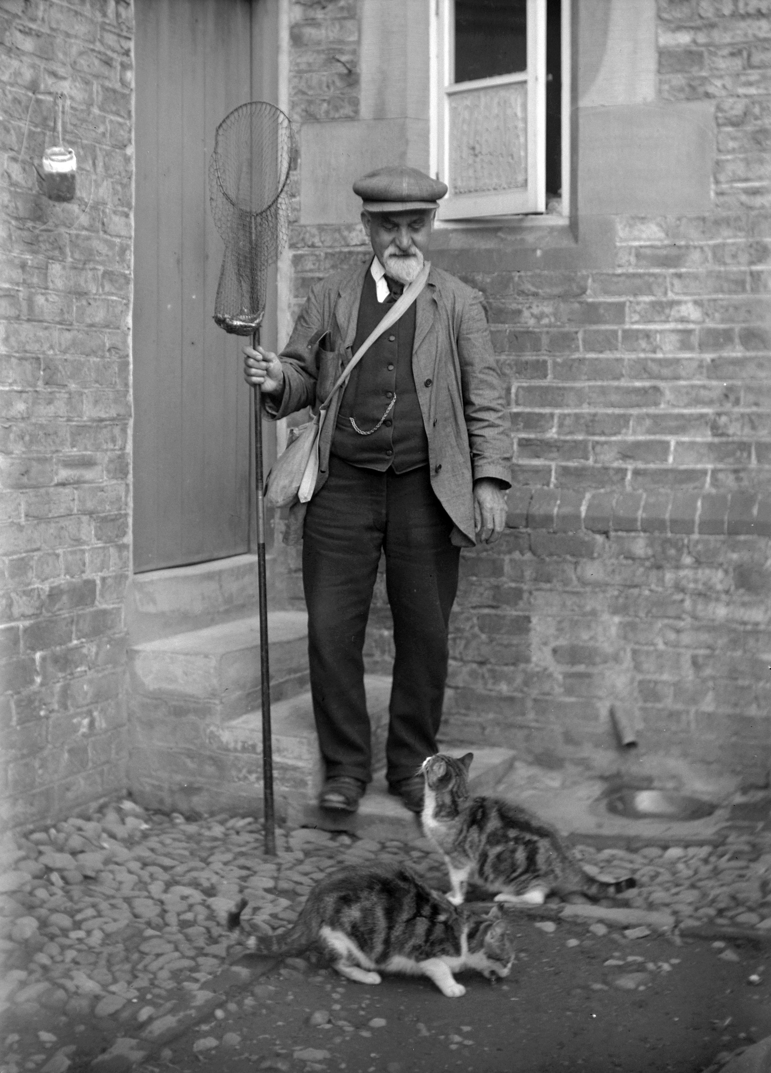 Fisherman and cats outside the Schoolhouse, Dunsforth (1915). From a collection of photographs by local amateur photographer Louisa Kruckenberg.