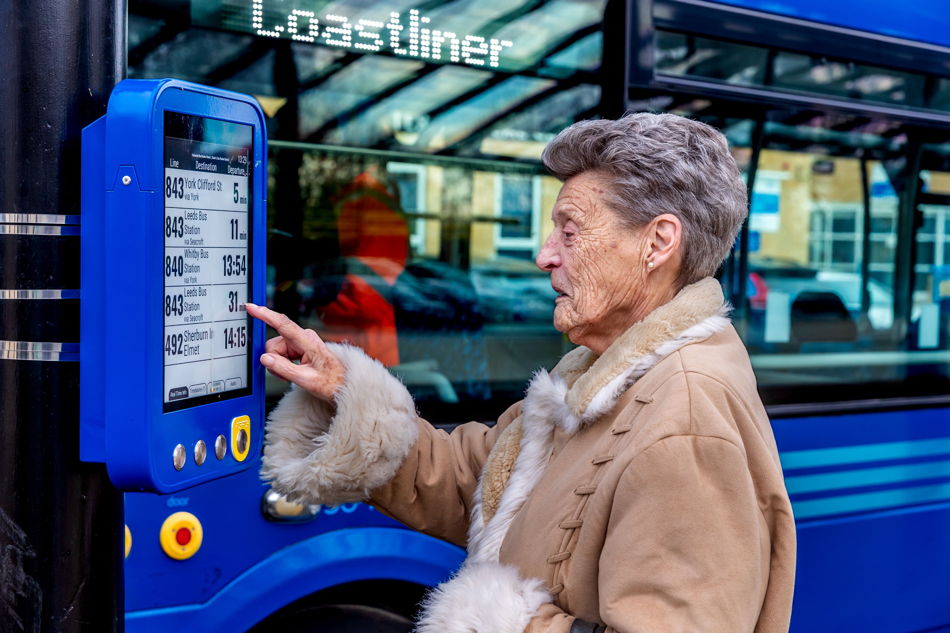 A lady looking at a bus station sign