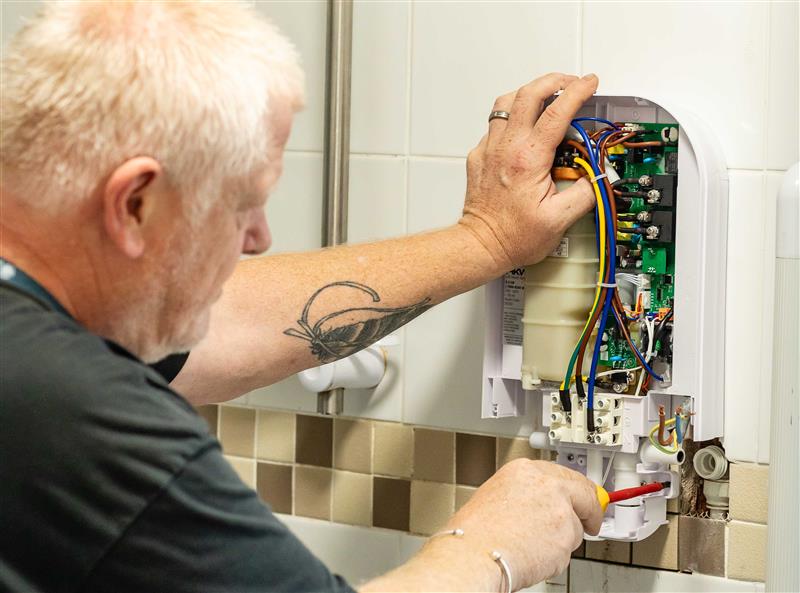 A council maintenance engineer repairing a shower