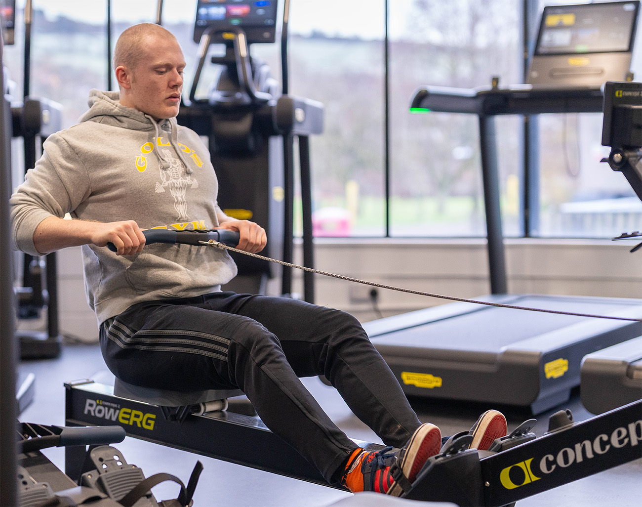 Man sat on a rowing machine in a gym