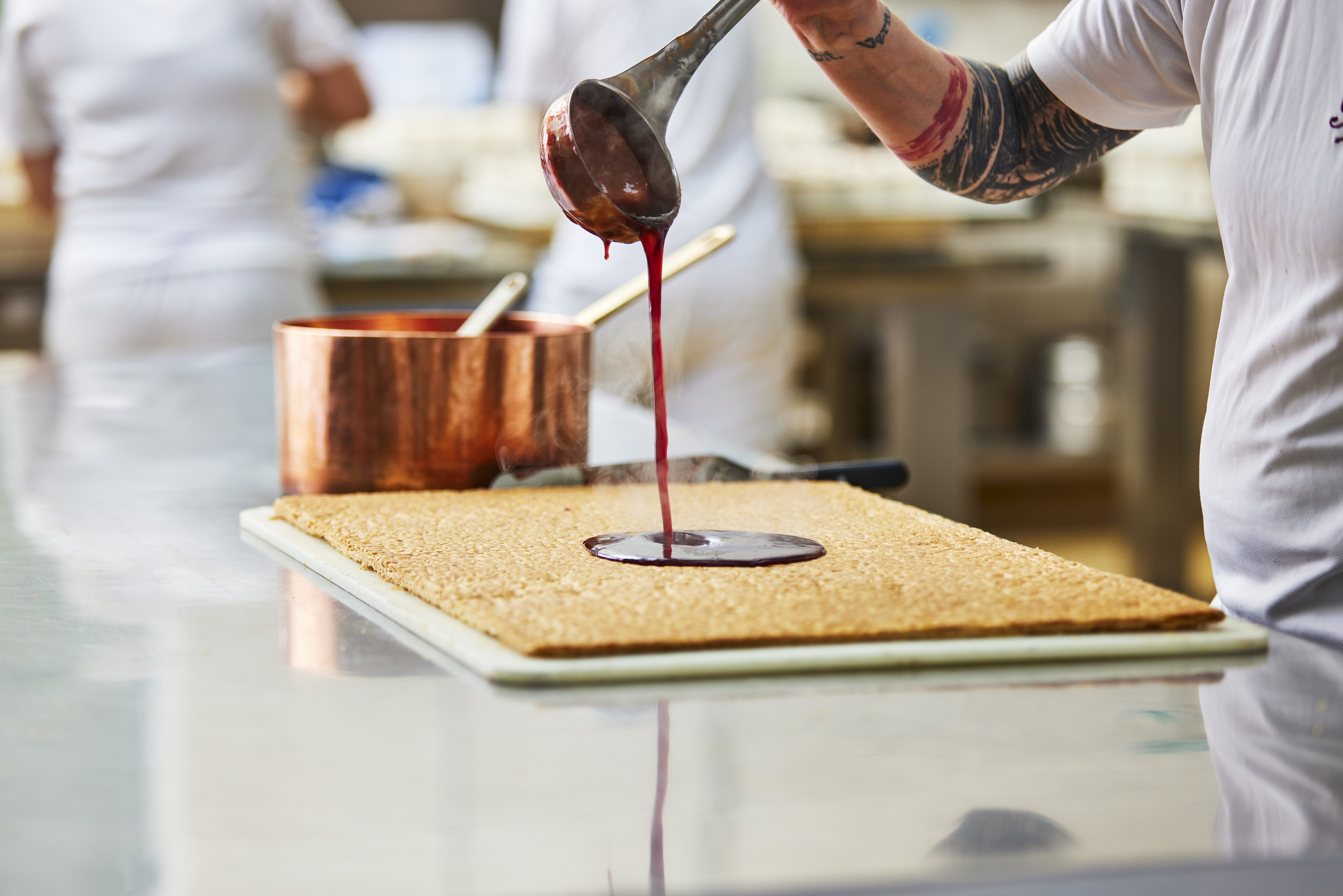 Member of Bettys pouring sauce over baked cake
