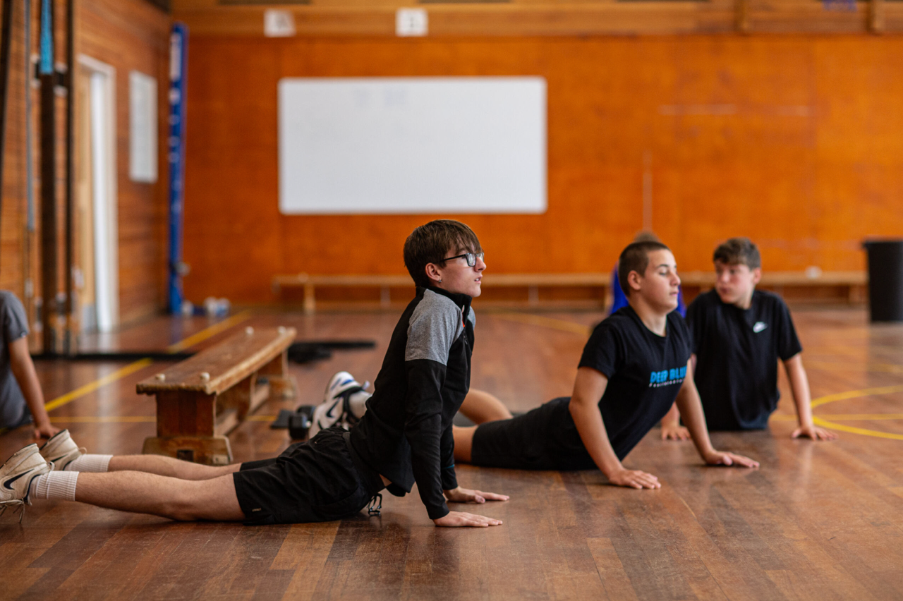 Group of young adults stretching on the floor in a sports hall