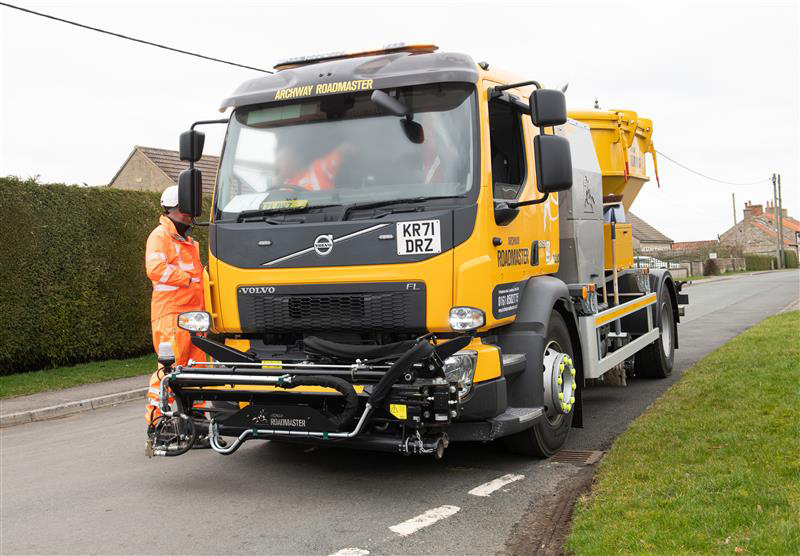 Person standing beside a highways vehicle in the road