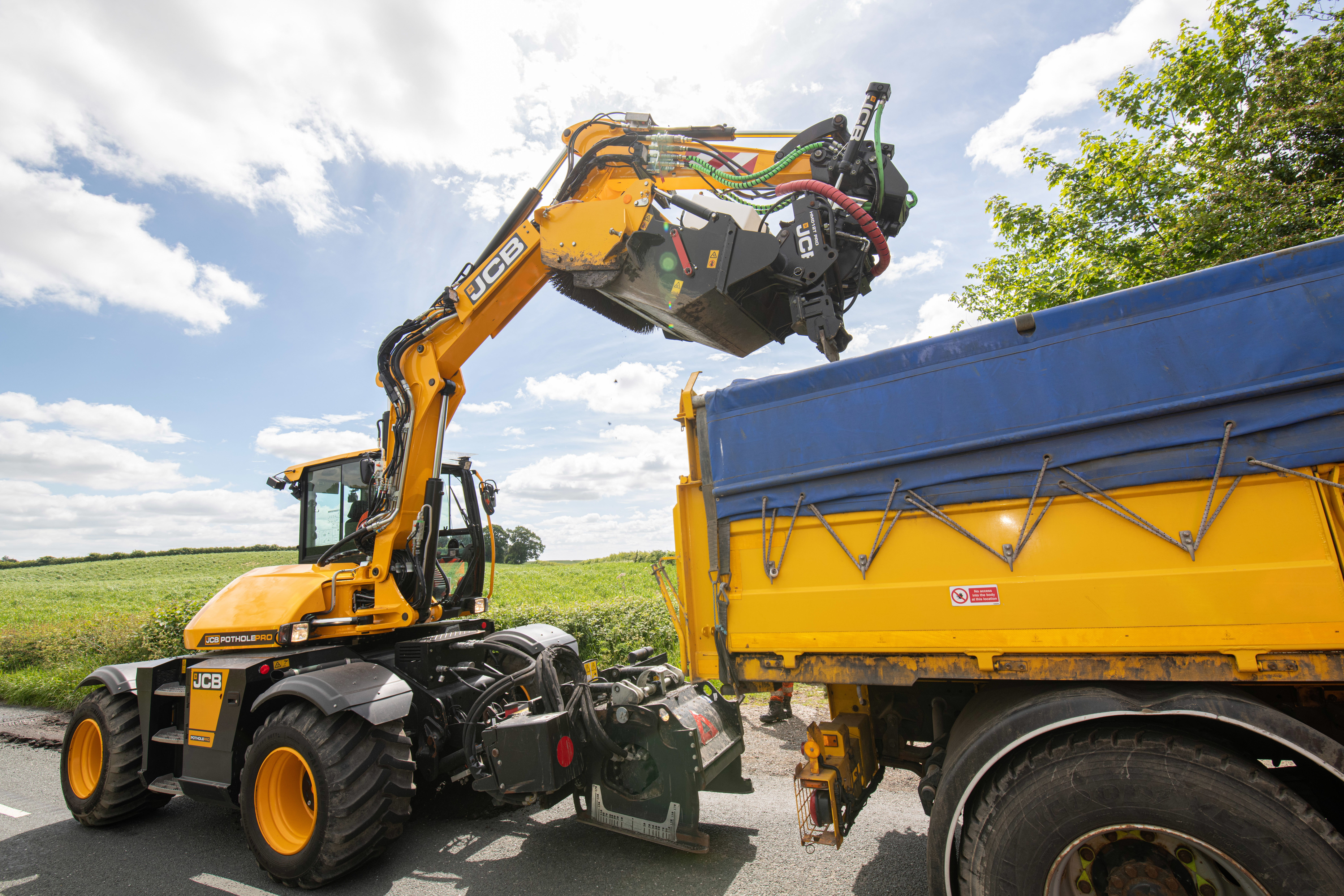 Two highway maintenance vehicles working on a stretch of road on a sunny day