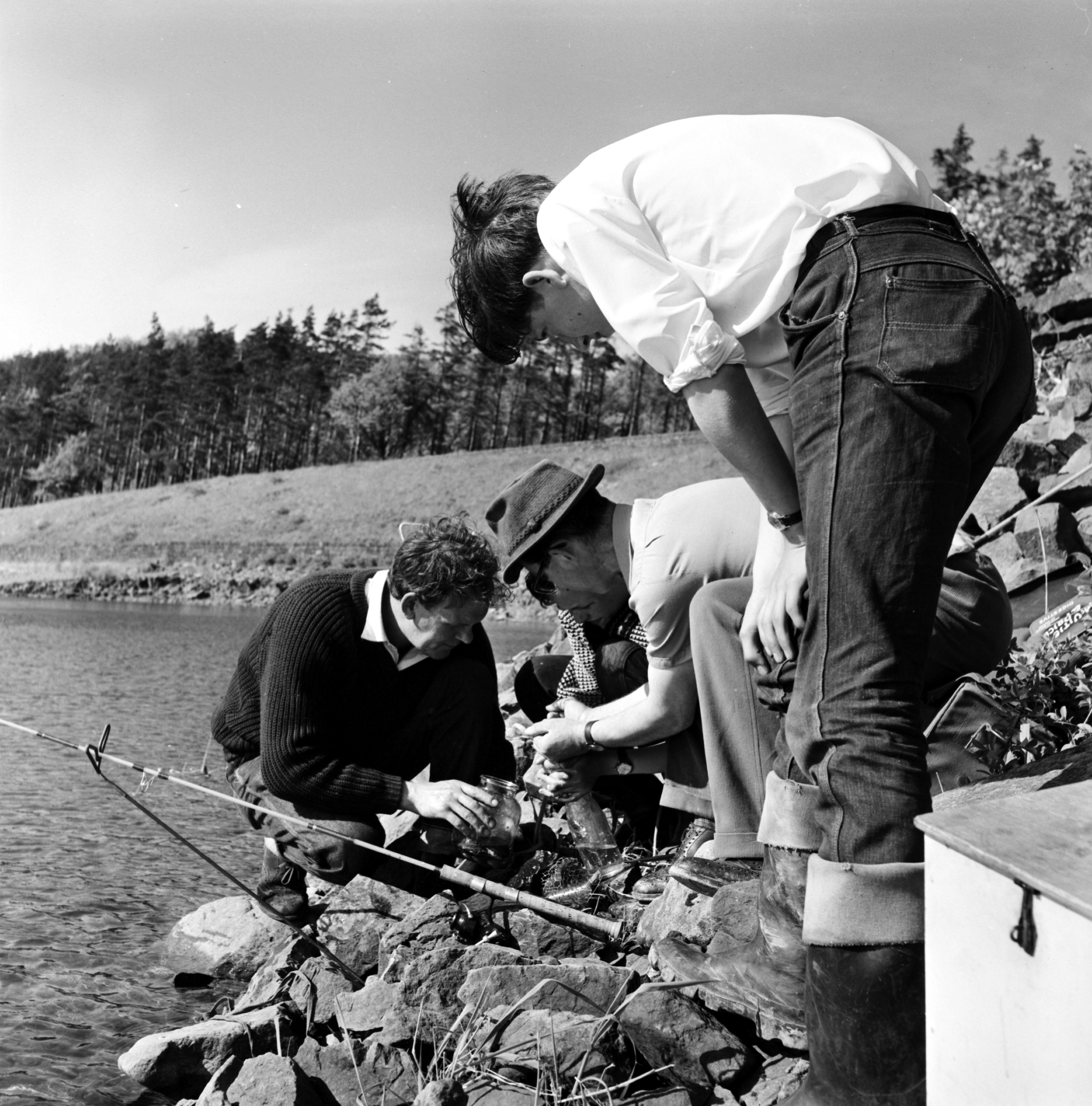Black and white photo of a group of adults fishing at Swinsty Reservoir in the 20th century. From the Bertram Unné photographic collection.