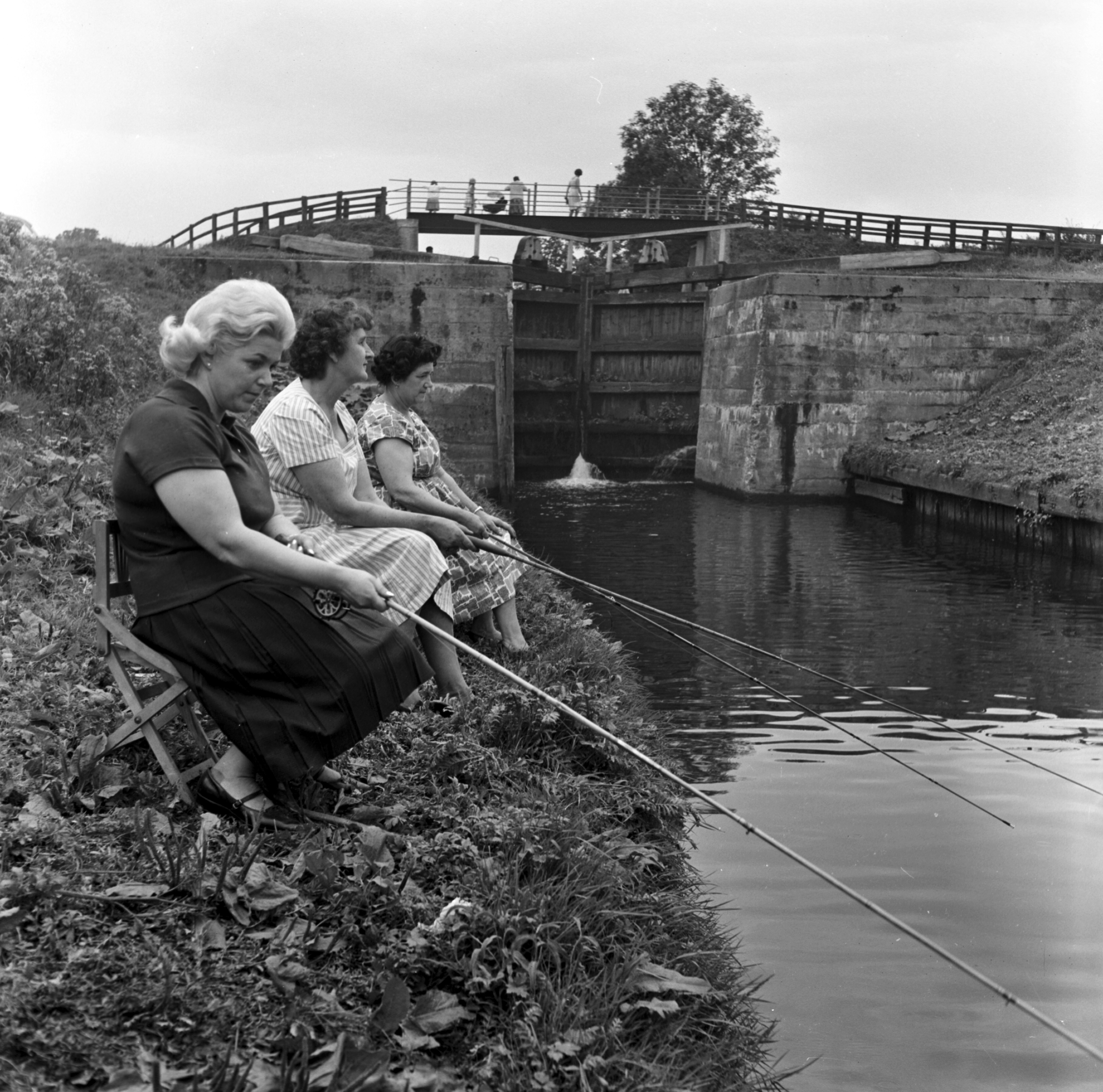 Black and white photo of women fishing at Milby Lock on the River Ure in the 20th century. From the Bertram Unné photographic collection.