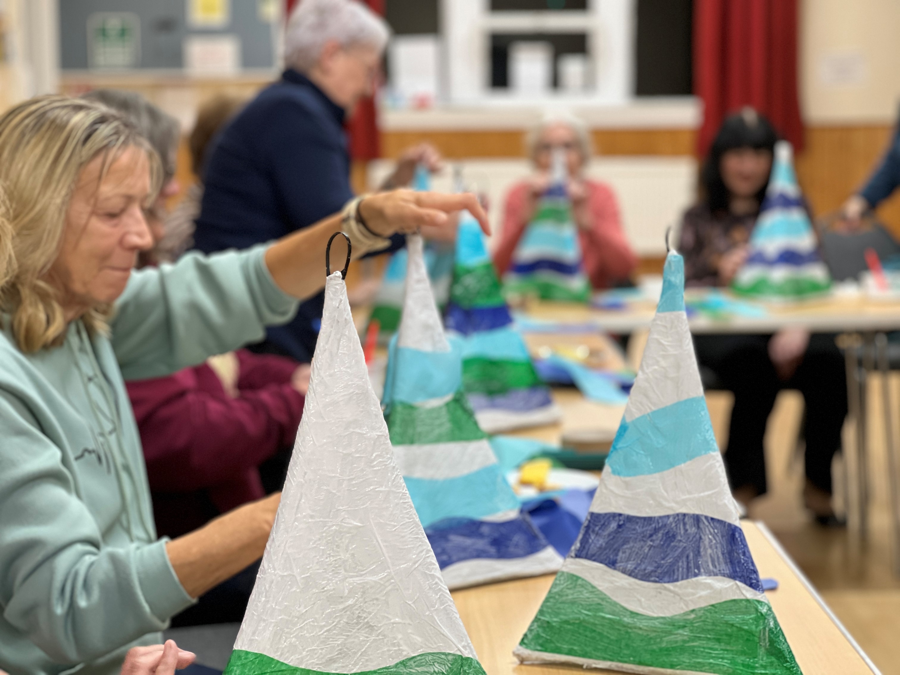 Group of adults sitting a long tables making lanterns