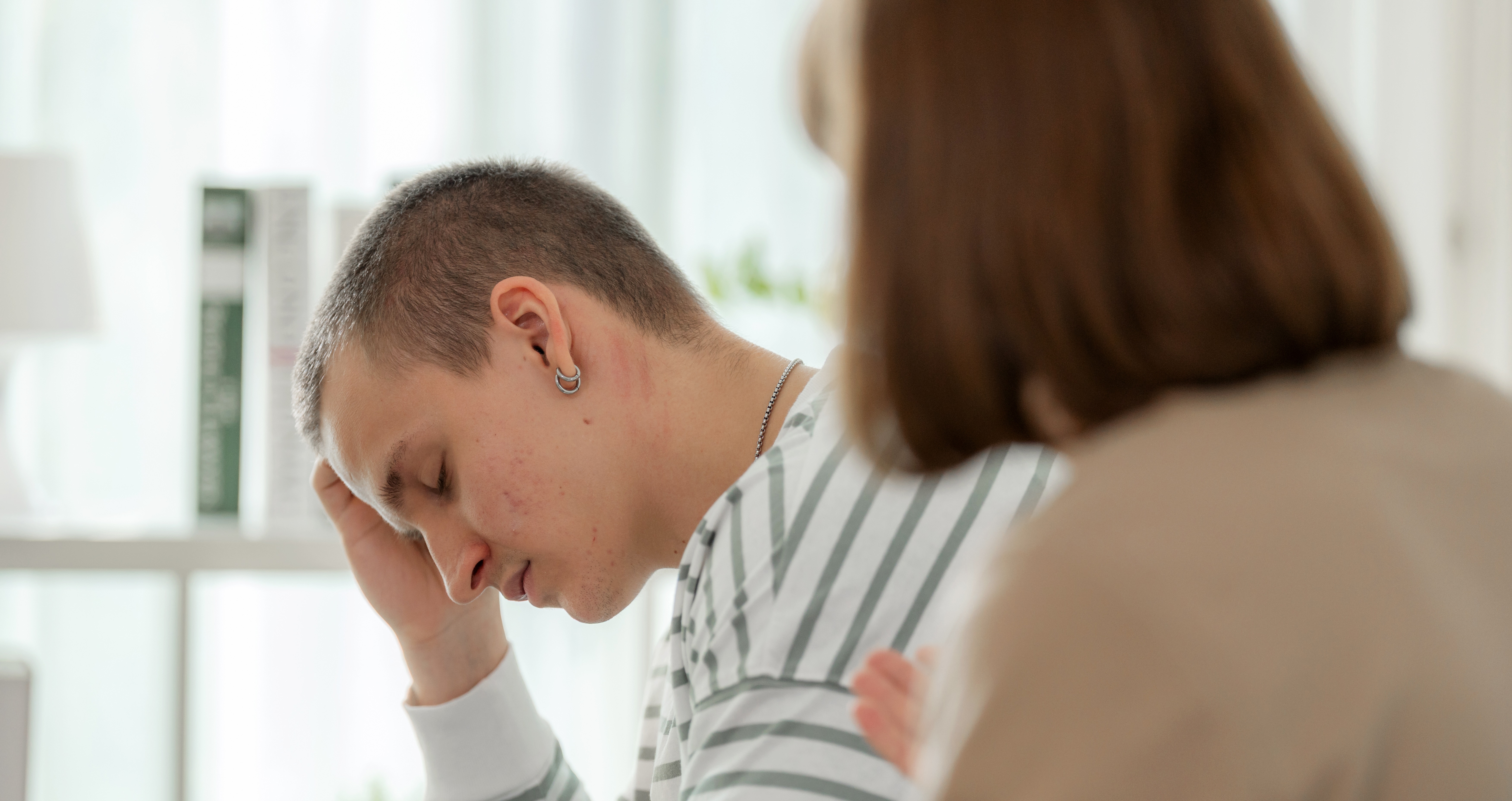 Person holding their head while someone talks to them
