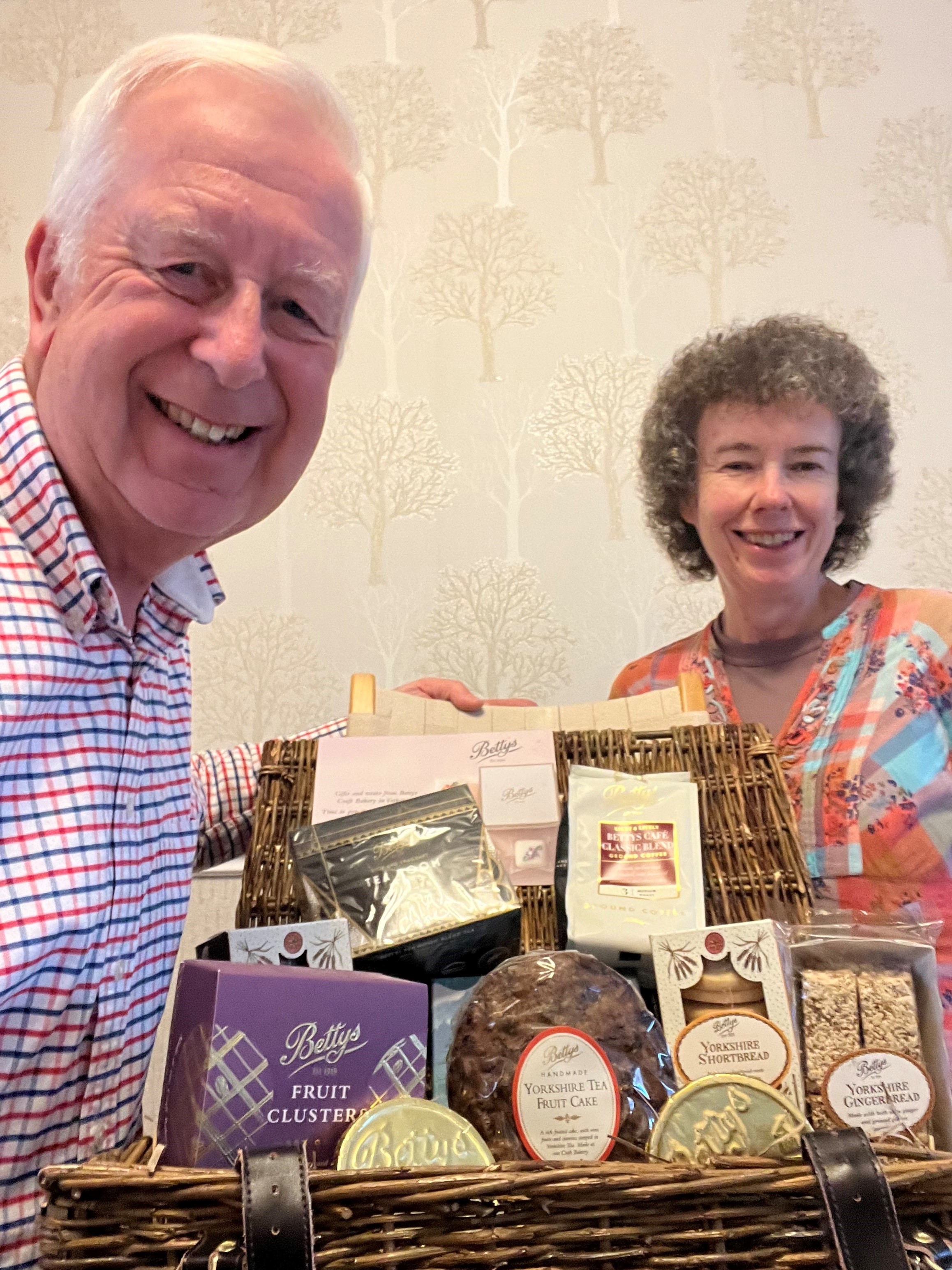 Couple smiling holding a hamper filled with goodies from Bettys