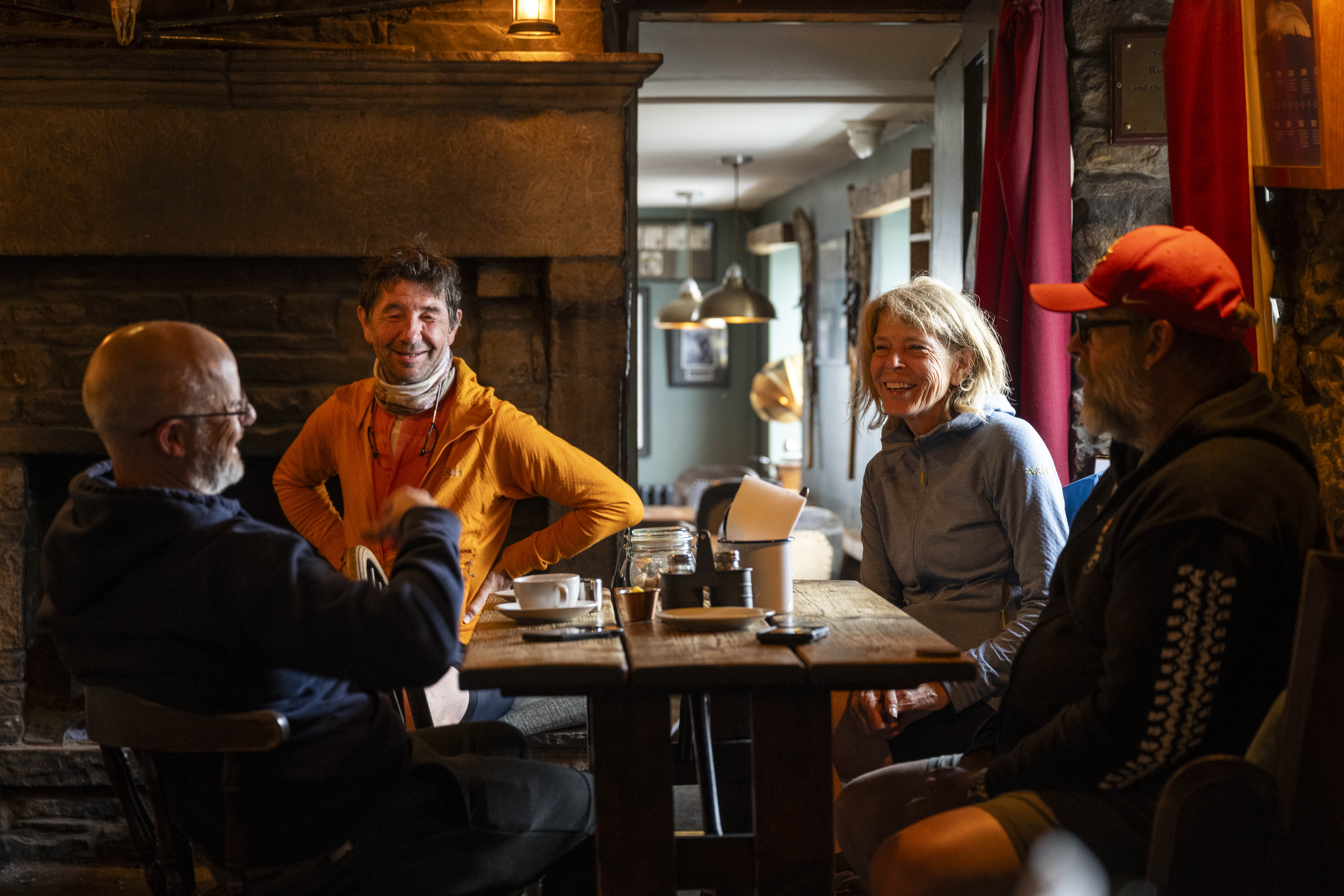Group of four adults sitting at a wooden table in conversation