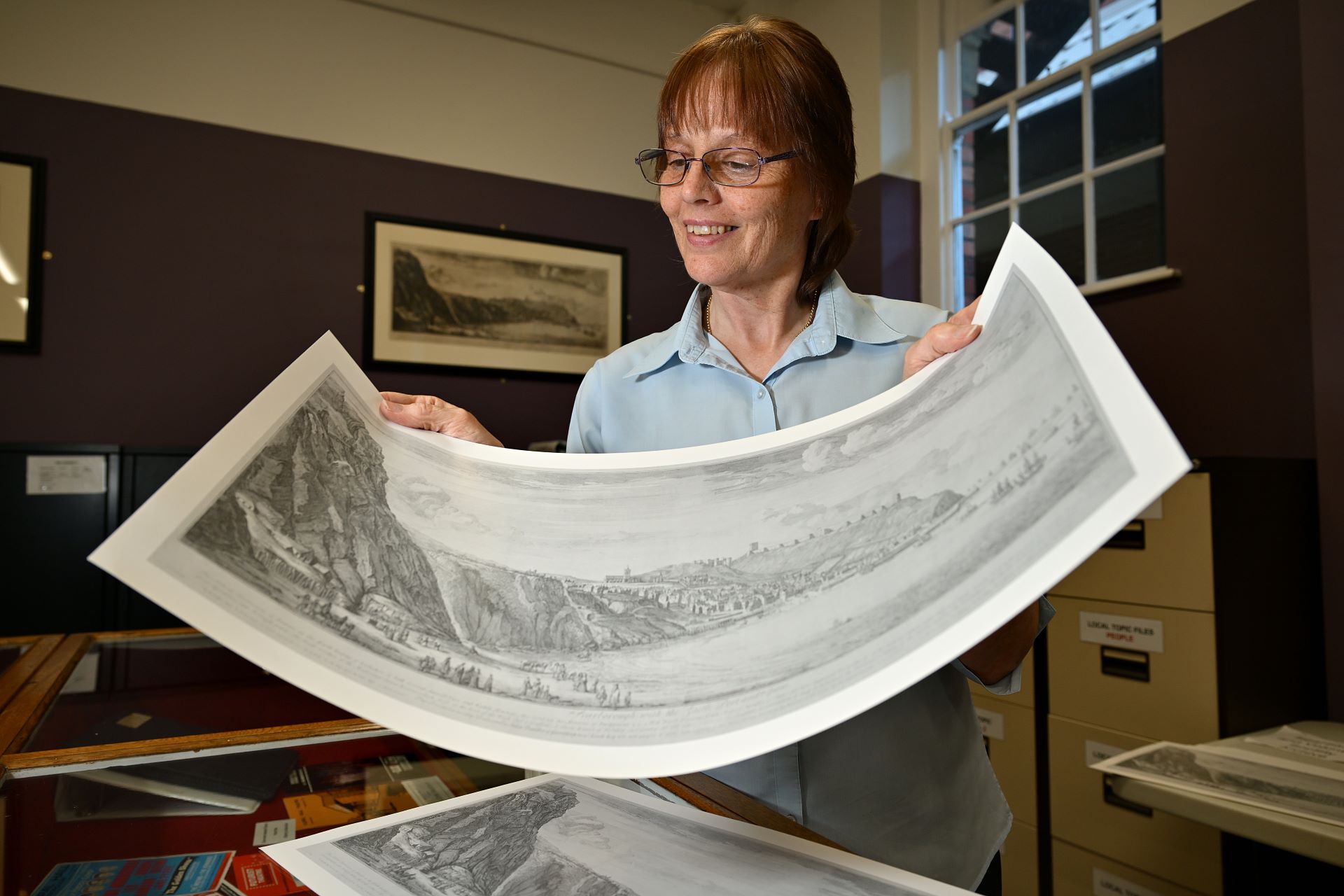 "An adult standing looking at a large black and white print
